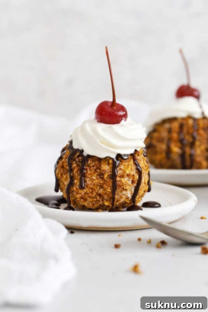 Front view of gluten-free fried ice cream topped with whipped cream, chocolate syrup, and a maraschino cherry