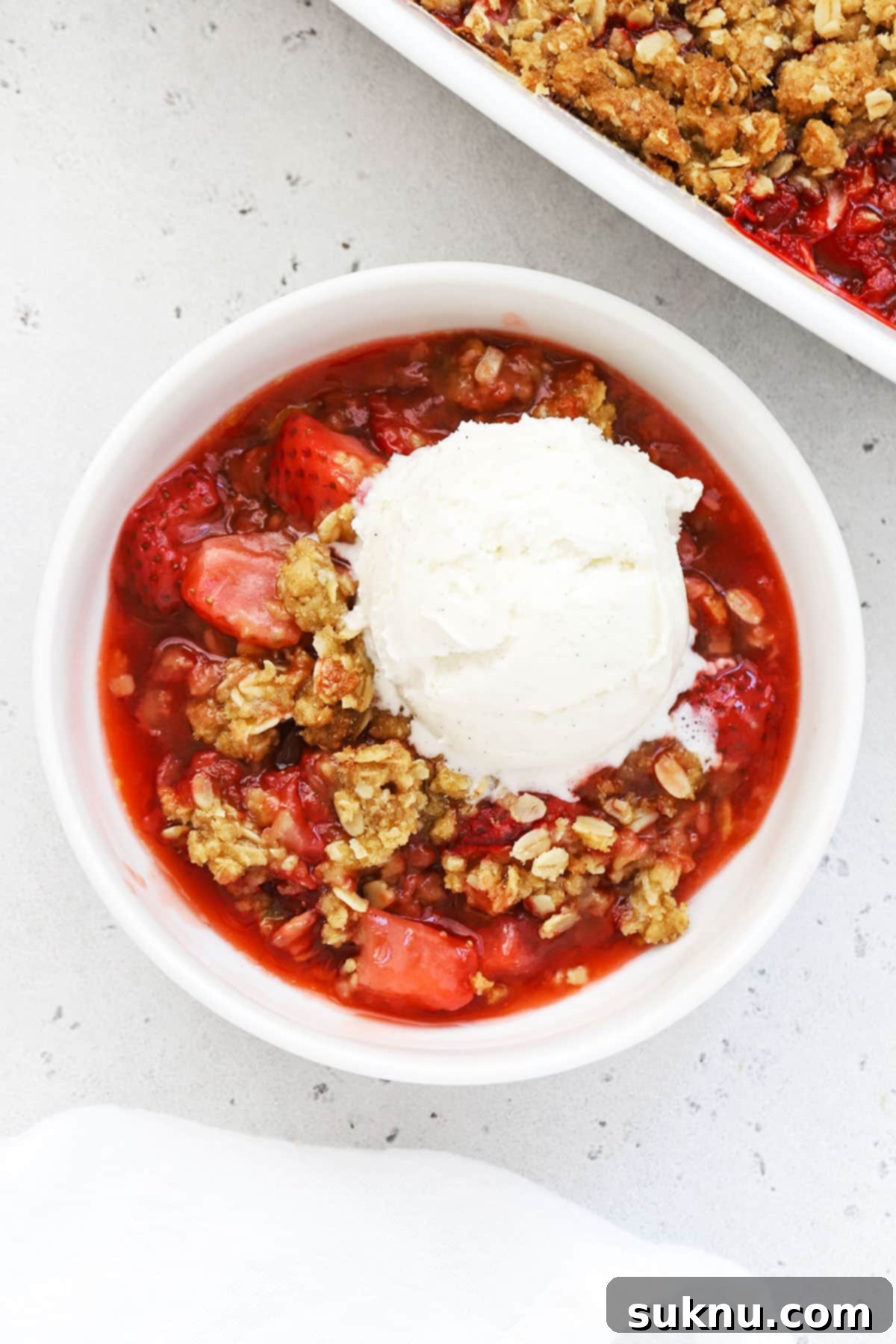 Gluten Free Strawberry Crumble 5 Gluten-free strawberry crisp in a white bowl topped with vanilla ice cream