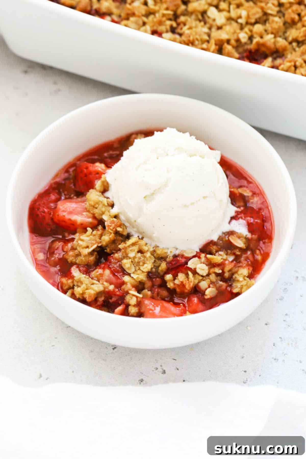 Gluten Free Strawberry Crumble 6 Gluten-free strawberry crisp in a white bowl topped with vanilla ice cream