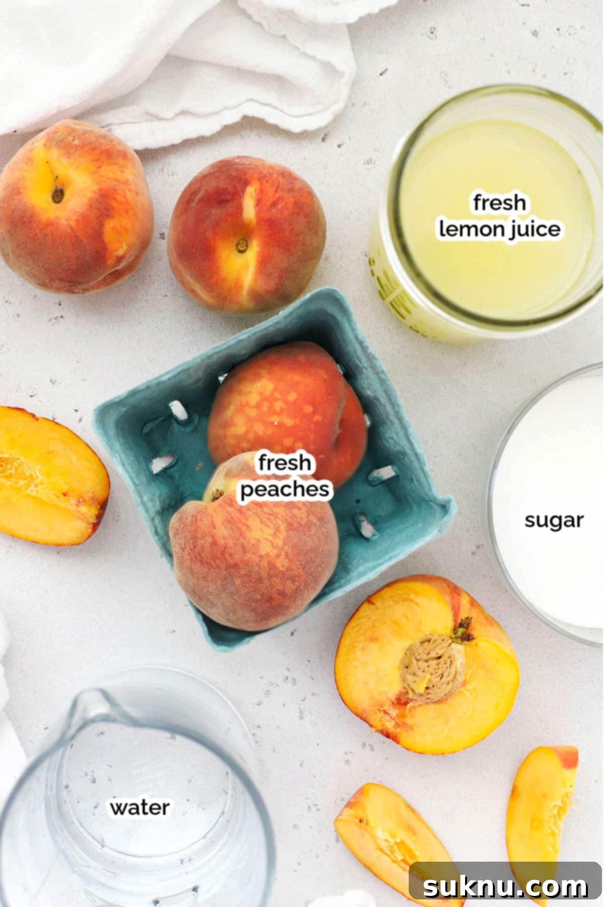 A flat lay image showing fresh peaches, lemons, sugar, and a pitcher of water, the simple ingredients for homemade peach lemonade.