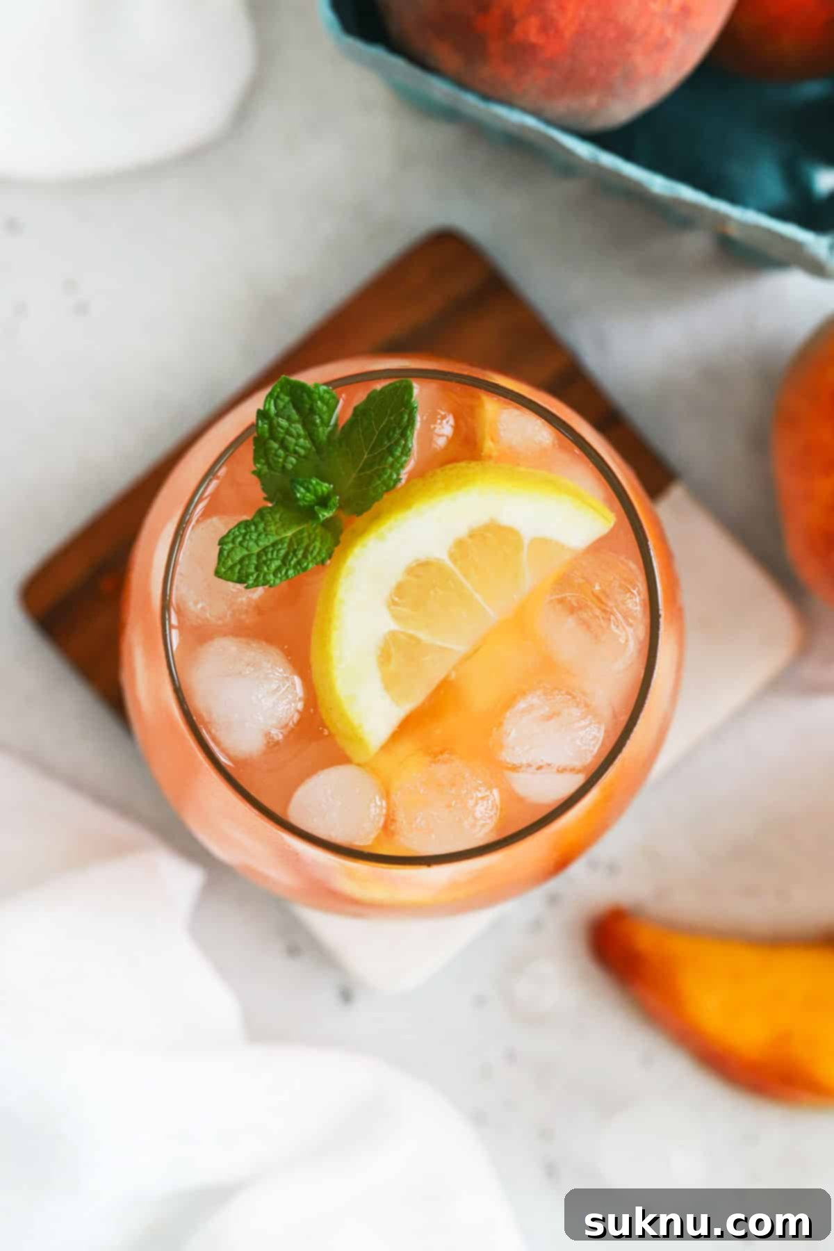 A single glass of homemade peach lemonade, beautifully garnished with a sprig of fresh mint and a peach slice, ready to be enjoyed.