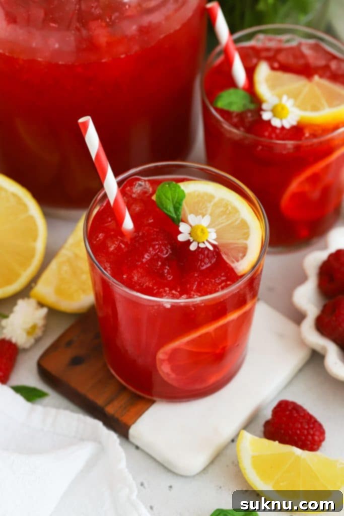 Glasses of fresh raspberry lemonade garnished with mint and lemon slices, a perfect summer drink.
