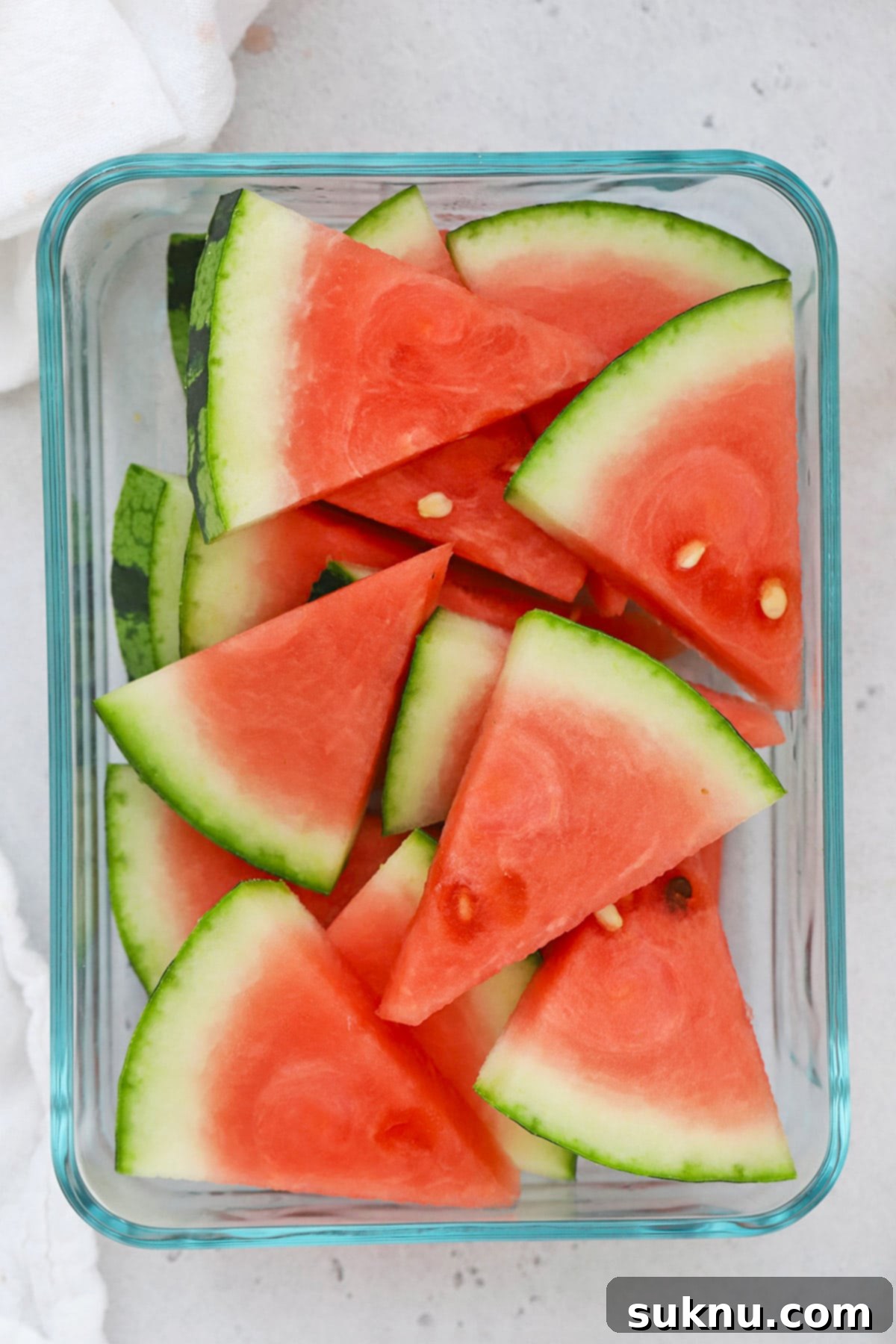 Overhead view of sliced watermelon wedges in a glass container, ready for a refreshing drink.