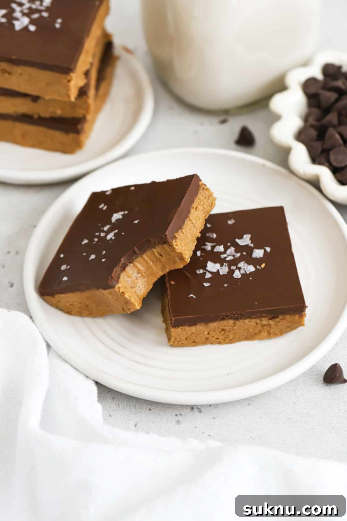 Gluten-free chocolate peanut butter bars stacked attractively on a white plate with a sprinkle of toppings