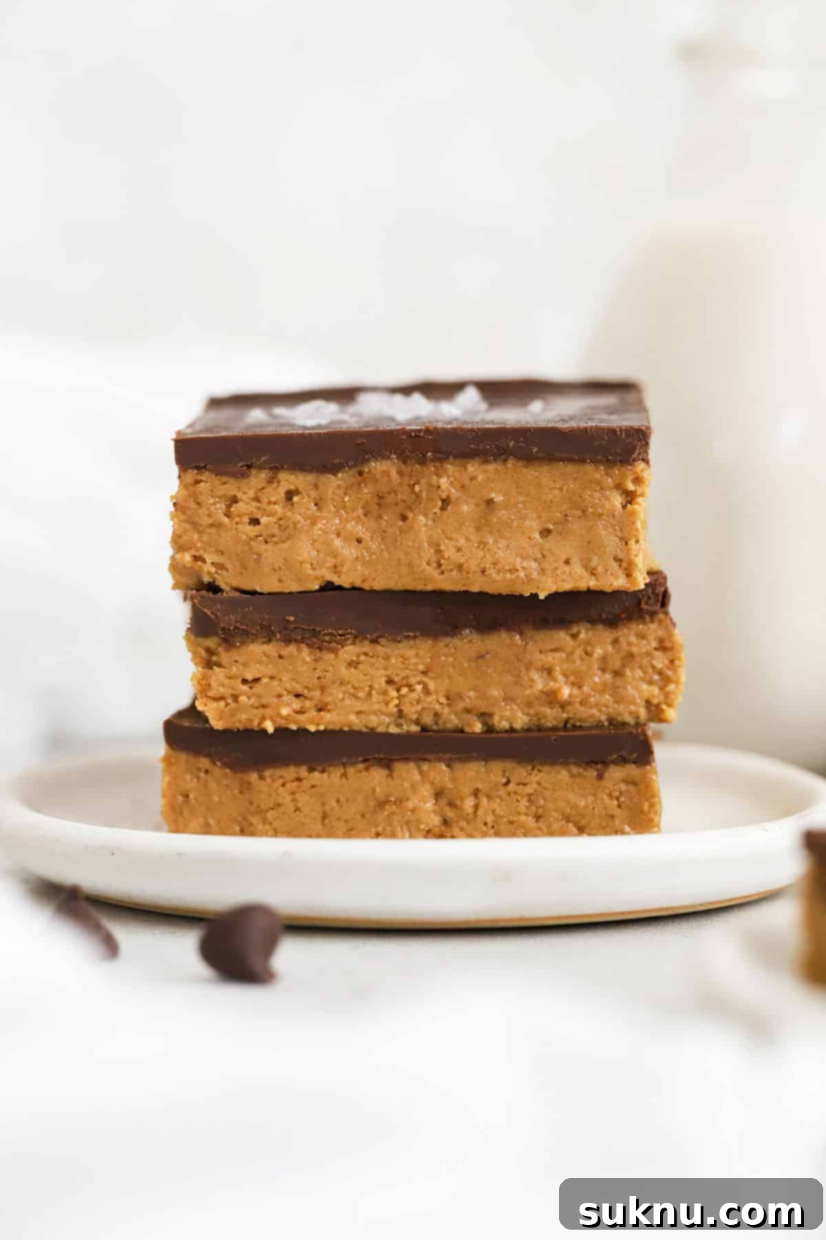 Gluten-free chocolate peanut butter bars stacked on a white plate with other sweet treats
