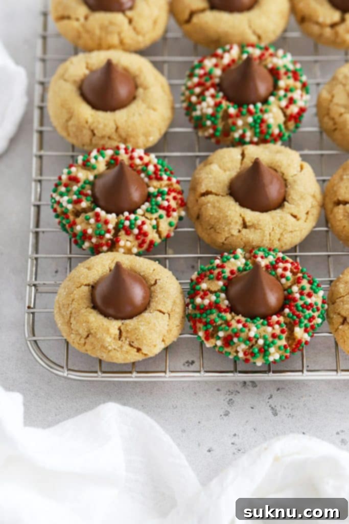 Gluten-free peanut butter blossoms cooling on a wire rack, some rolled in festive sprinkles