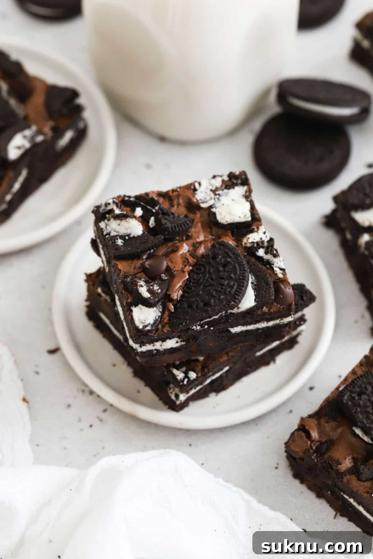 Fudgy gluten-free Oreo brownies stacked on a white plate, showcasing their rich texture and cookie layers.