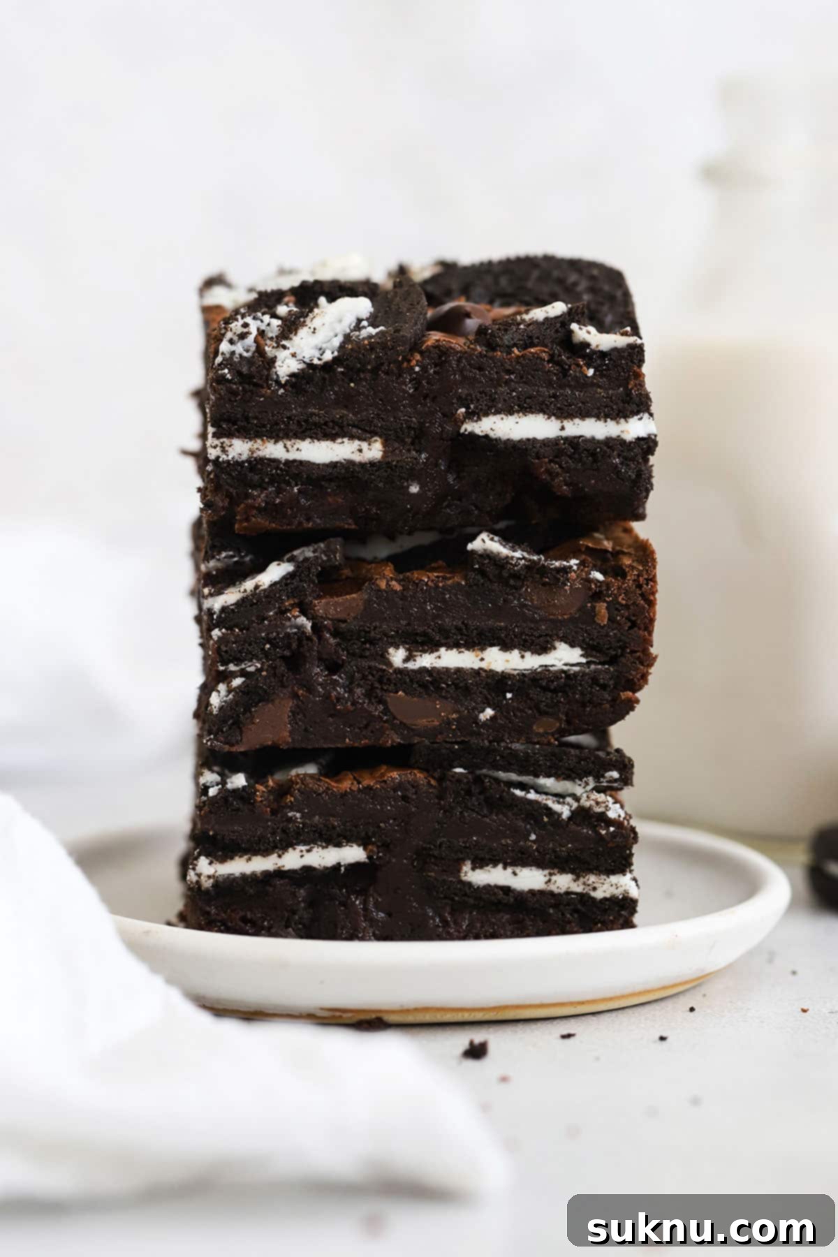 Fudgy gluten-free Oreo brownies stacked appealingly on a white plate, highlighting their rich chocolate and cookie texture.