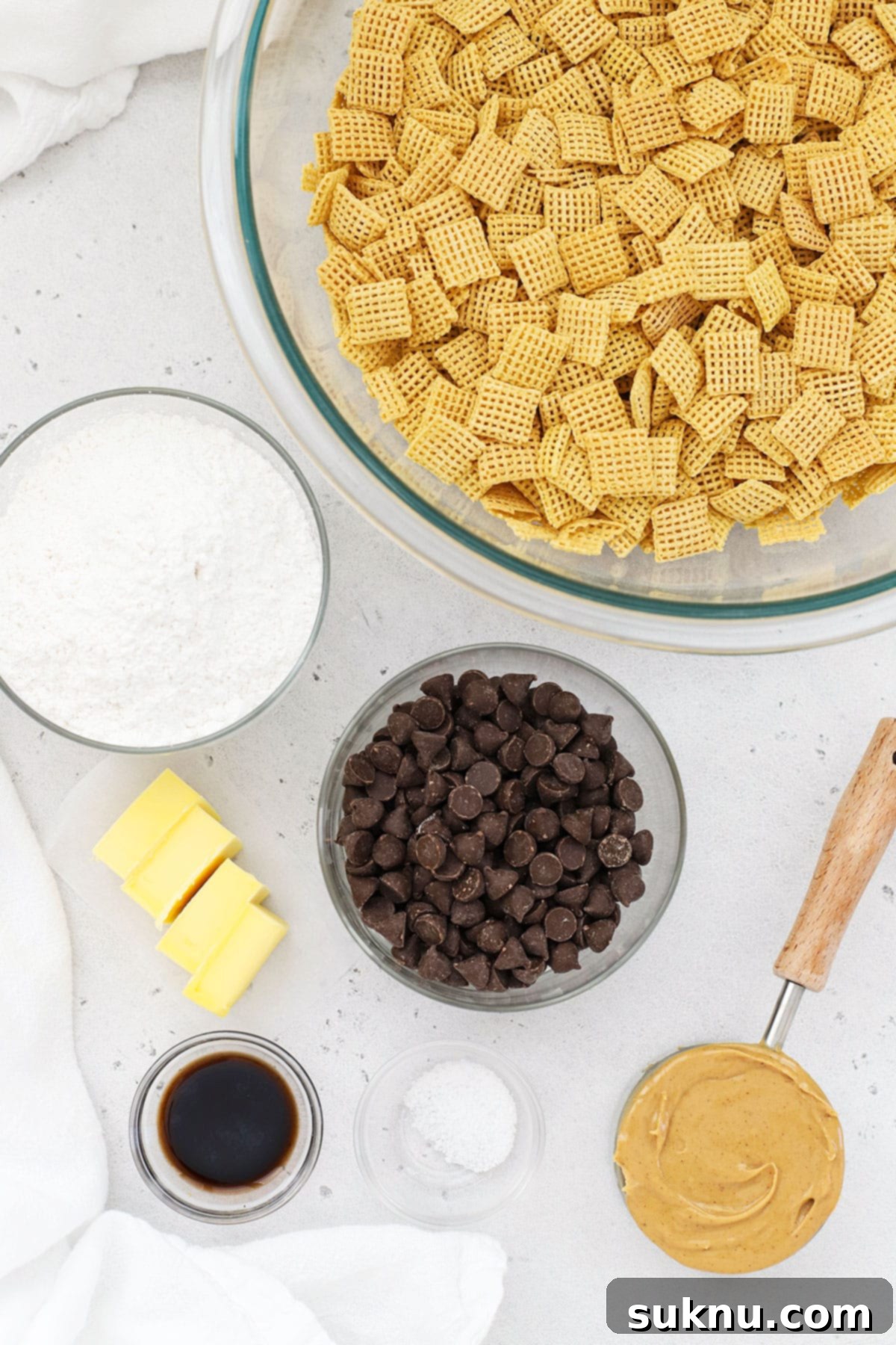 A selection of ingredients laid out for making gluten-free puppy chow, including Chex cereal, chocolate chips, peanut butter, and powdered sugar.