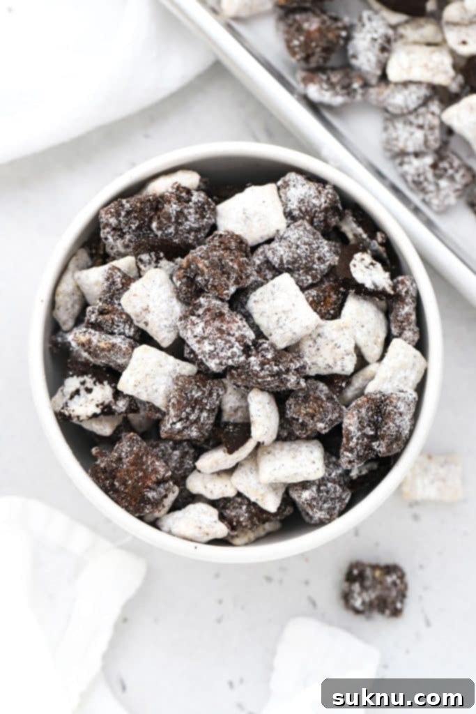 A bowl filled with gluten-free cookies and cream muddy buddies, featuring crushed gluten-free sandwich cookies for added texture.
