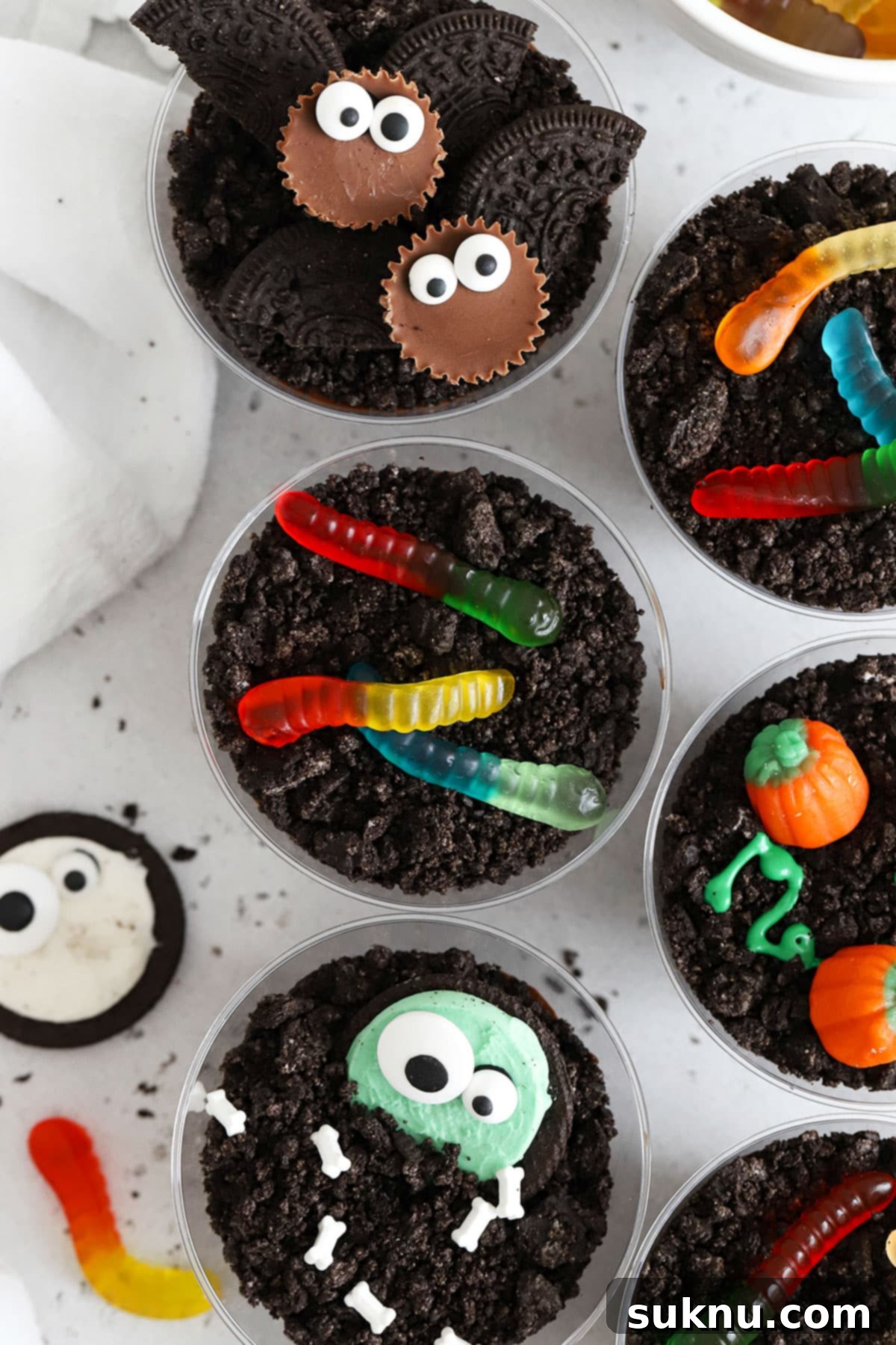 A vibrant close-up of various Halloween-themed gluten-free dirt pudding decorations, showcasing intricate monster faces and bat wings for a festive touch.
