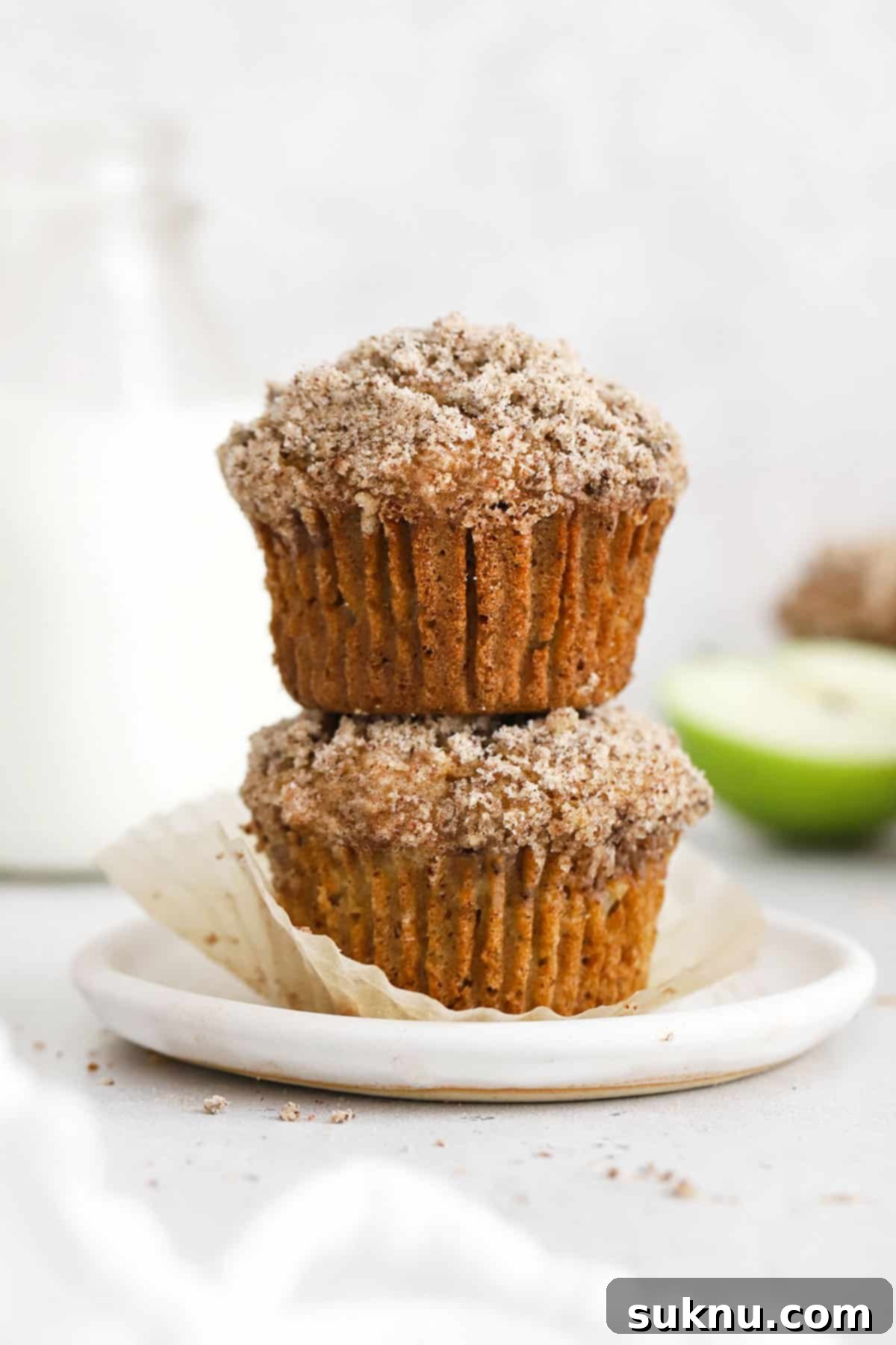 Two gluten-free apple muffins stacked on a white plate