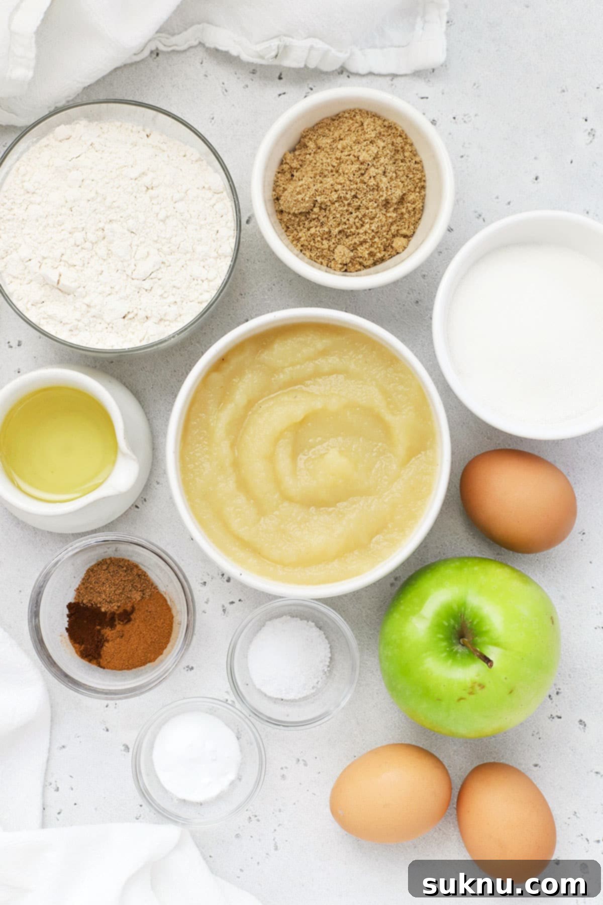 A flat lay image showcasing all the simple ingredients required to bake gluten-free applesauce muffins.