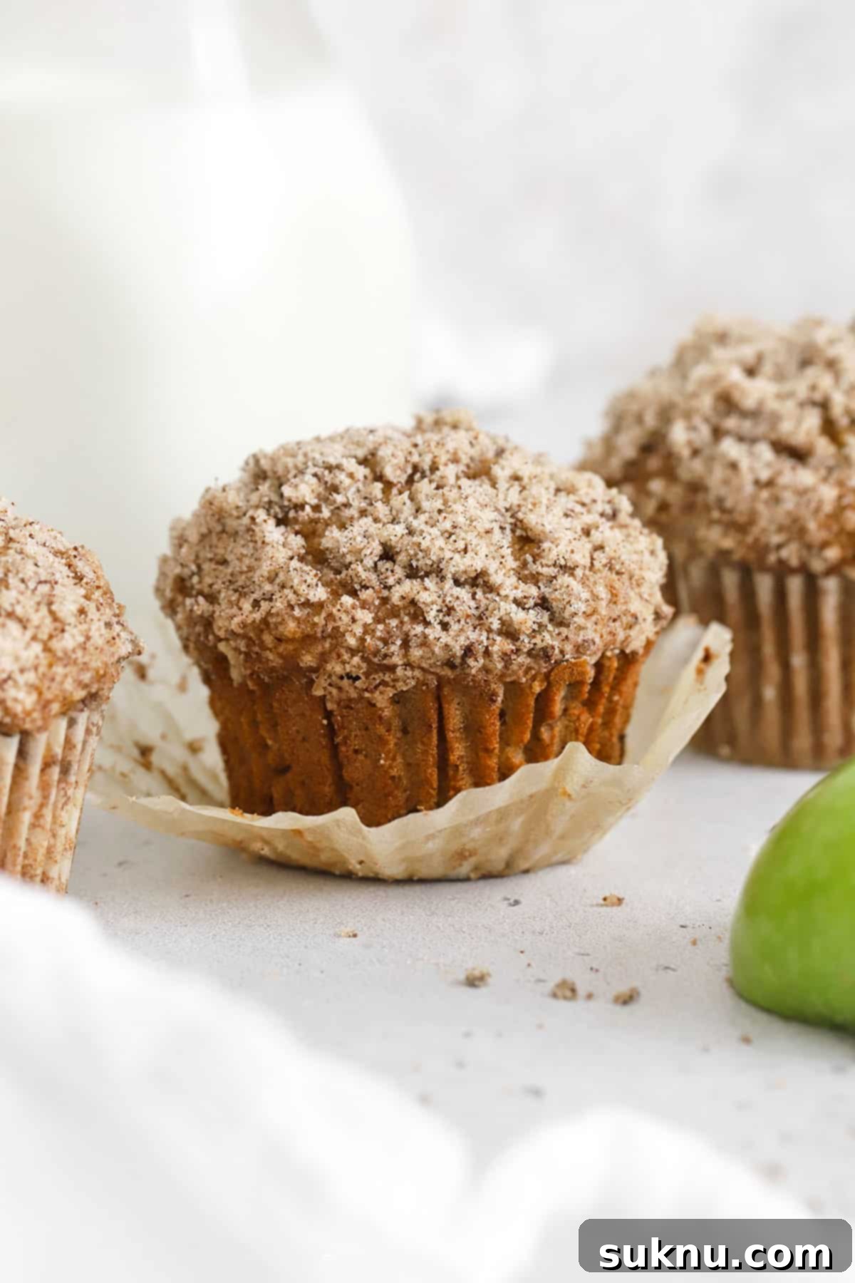 Three perfectly baked gluten-free applesauce muffins displayed on a pristine white background.