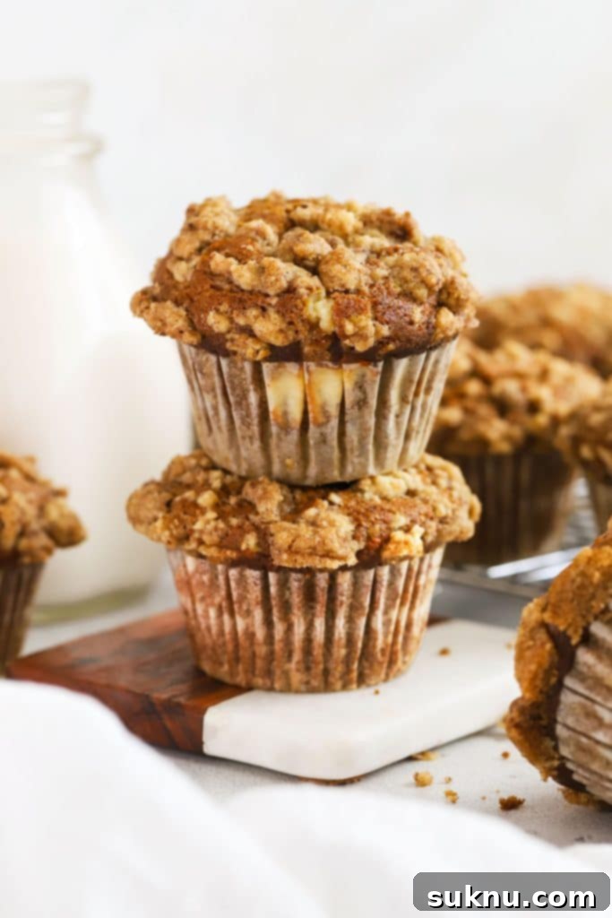 Two pumpkin cream cheese muffins stacked next to a bottle of milk