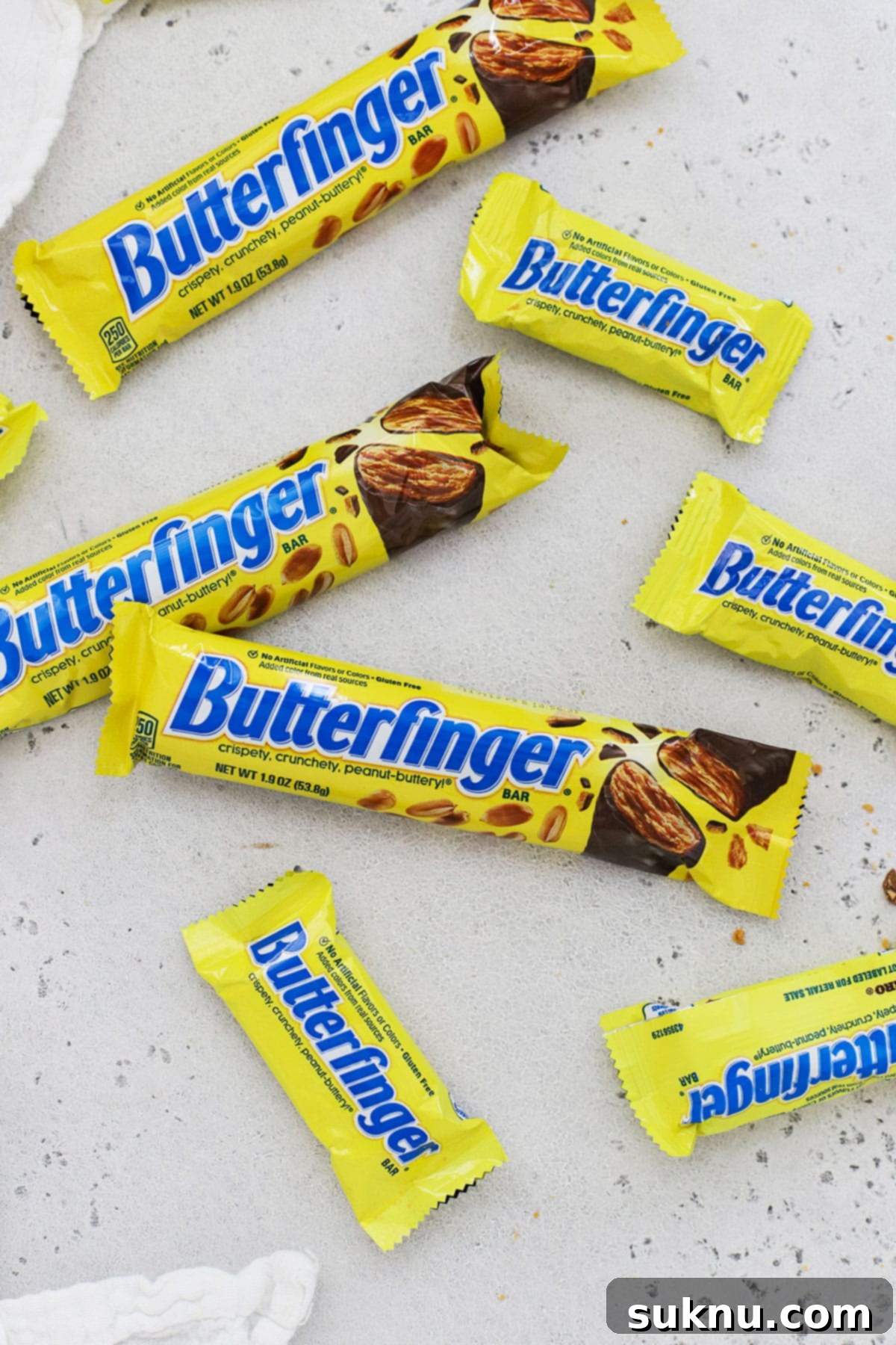 Different sizes of Butterfinger candy bars on a white background, highlighting their appeal for a gluten-free diet.