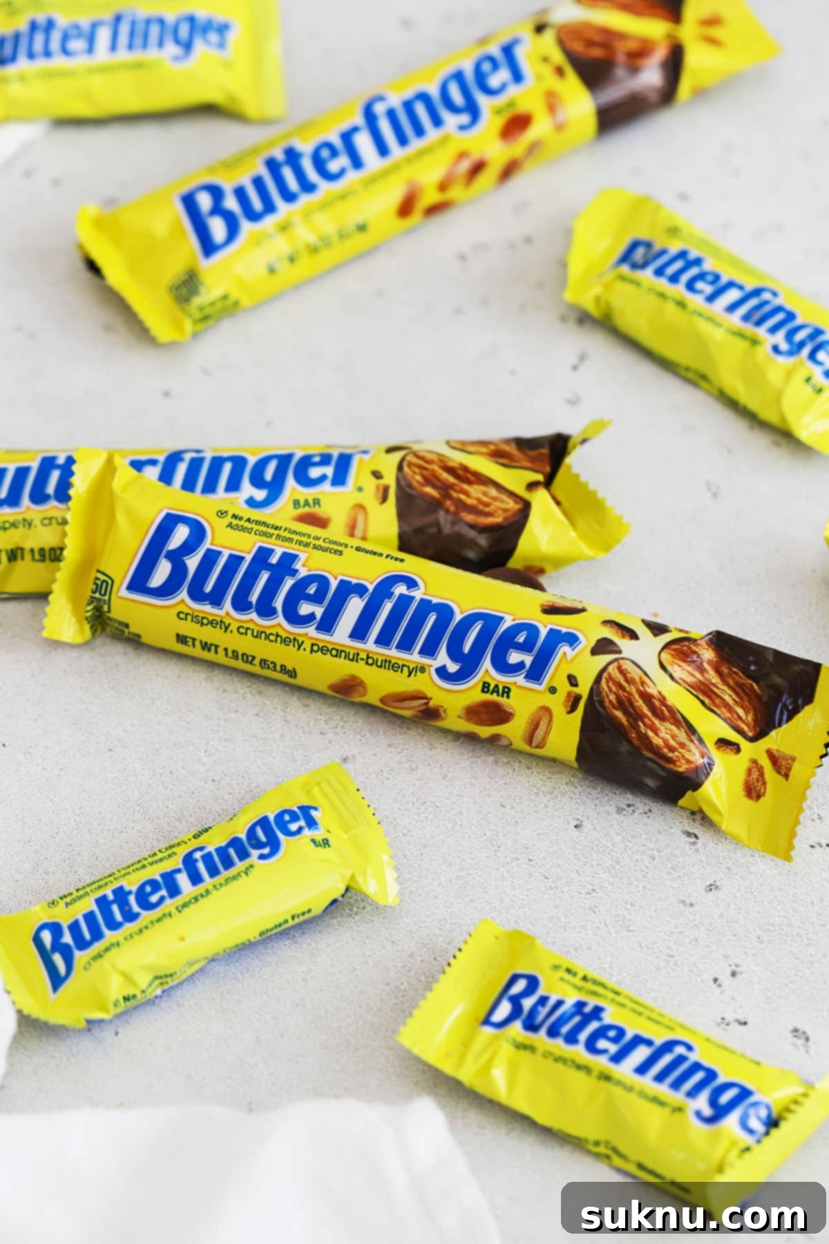 Multiple Butterfinger candy bars in various sizes displayed on a clean white background, emphasizing their availability for gluten-free consumers.