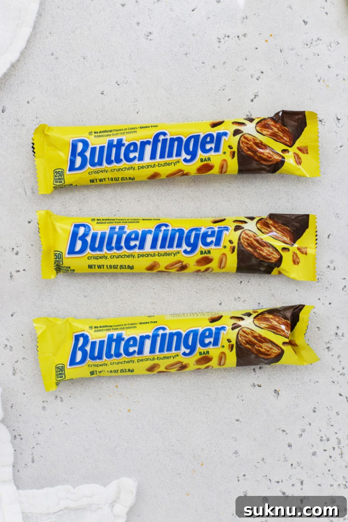 Three Butterfinger candy bars of different sizes arranged artfully on a white background, highlighting the distinct layers of the candy.