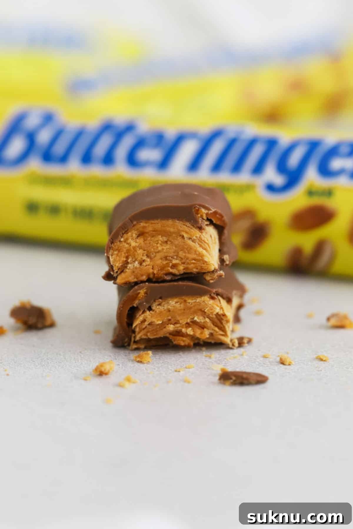 A Butterfinger candy bar expertly cut in half and stacked to reveal its crispy, layered interior, emphasizing its unique texture.