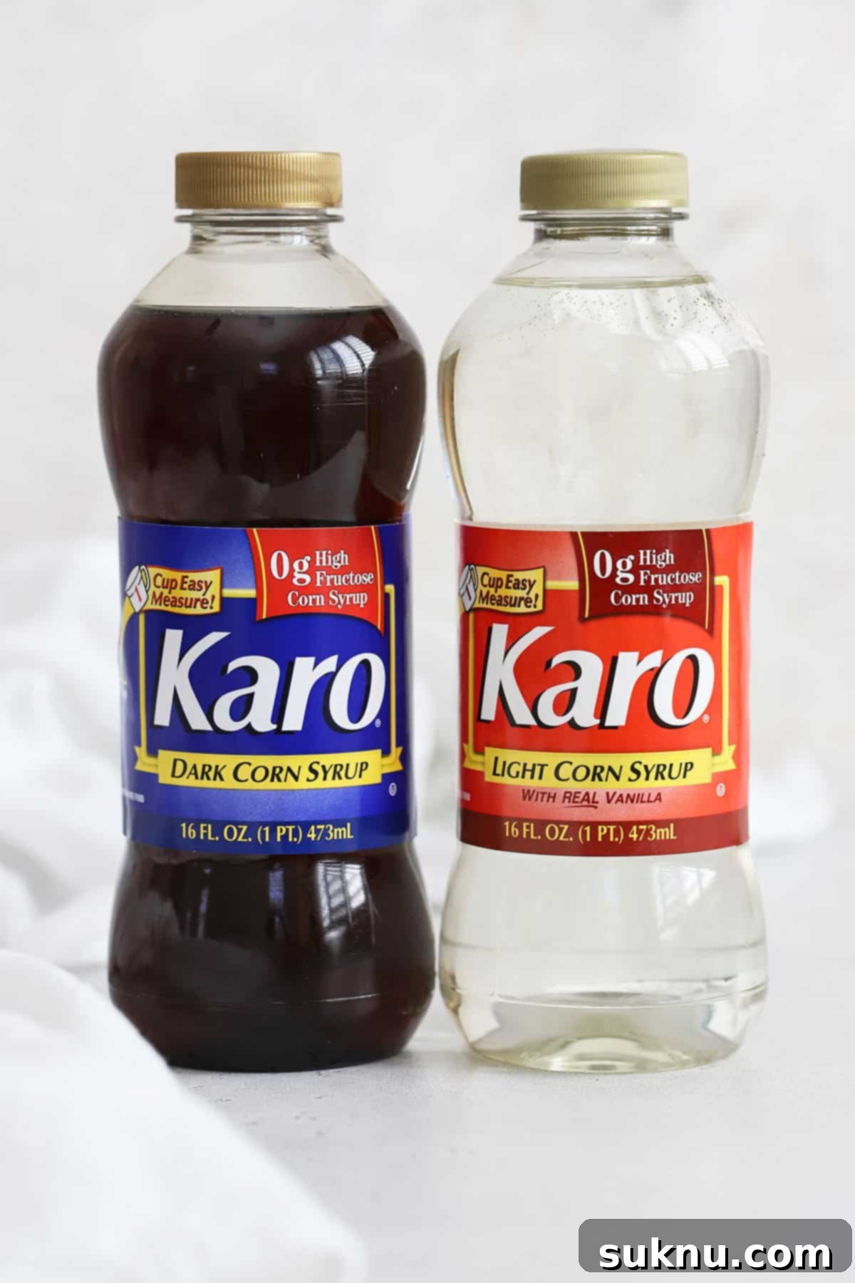 A bottle of Karo Dark Corn Syrup and a bottle of Karo Light Corn Syrup displayed on a pristine white background, emphasizing their distinct appearances.