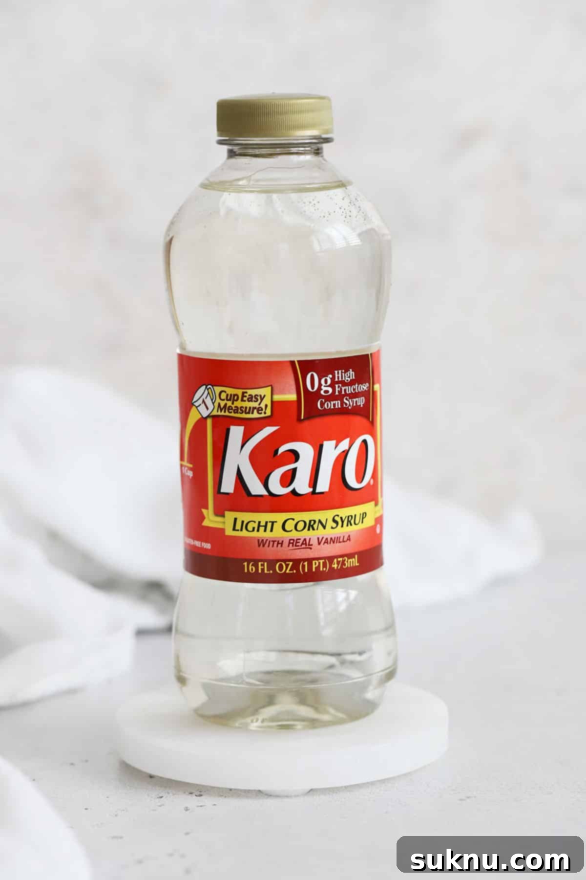 A bottle of light corn syrup stands alone on a clean white background, highlighting its clear liquid and simple packaging.