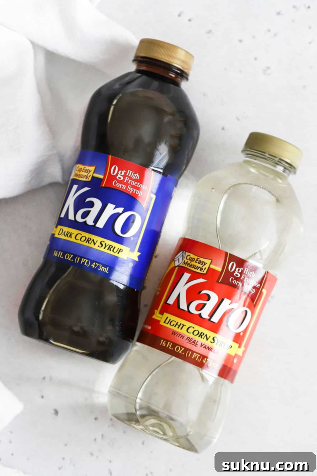 Two identical bottles of corn syrup, possibly light corn syrup, stand together on a simple white background, ready for use.