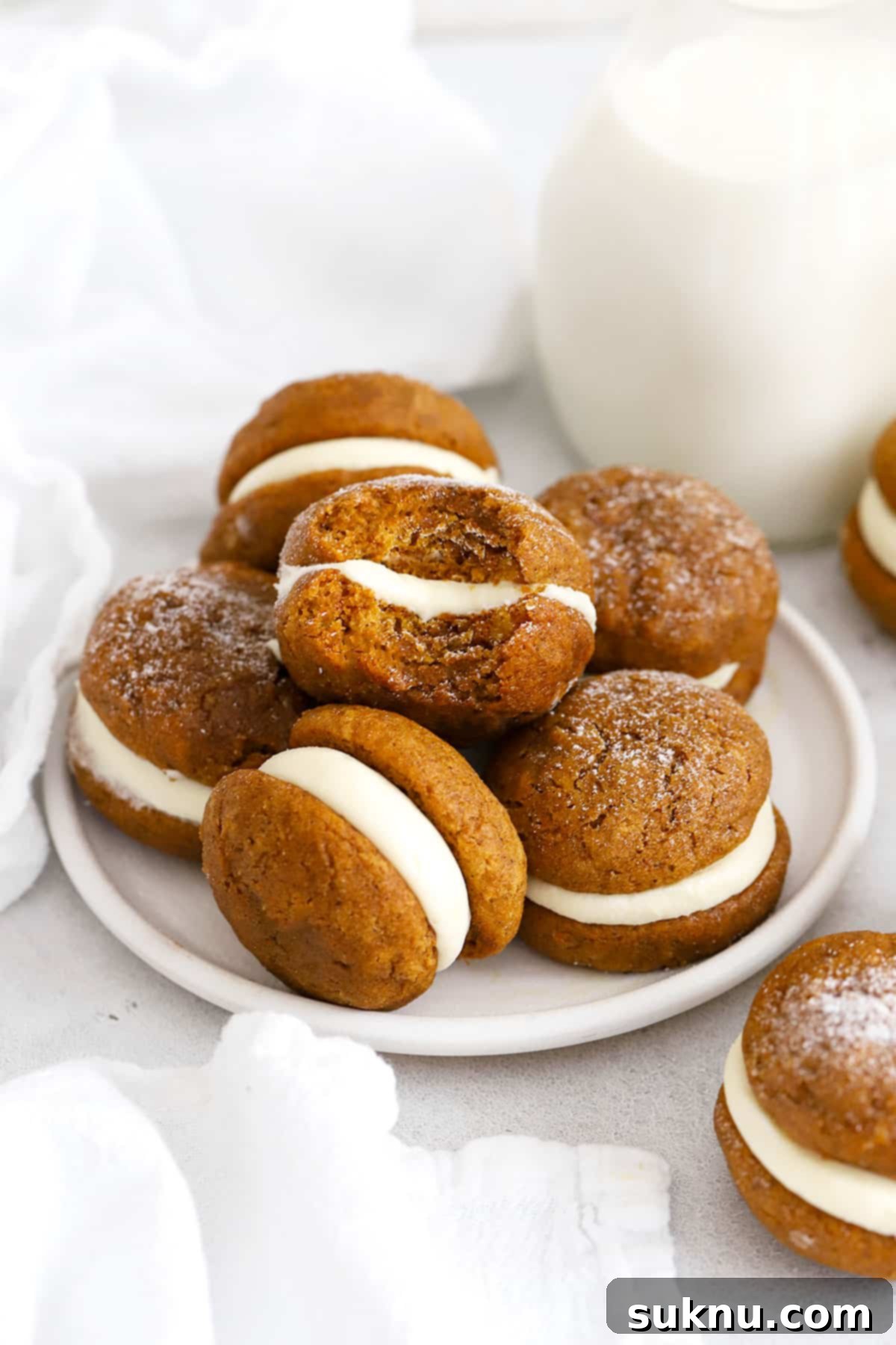 gluten-free pumpkin whoopie pies with cream cheese frosting stacked on a white plate