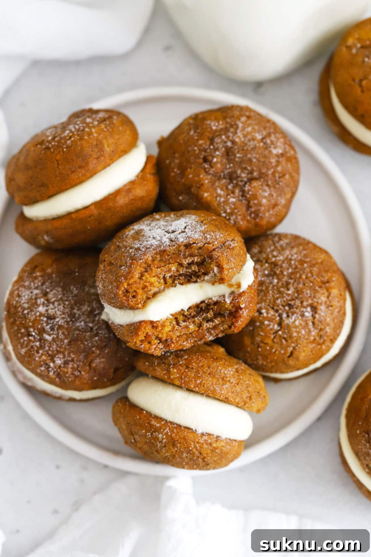 gluten-free pumpkin whoopie pies with cream cheese frosting stacked on a white plate