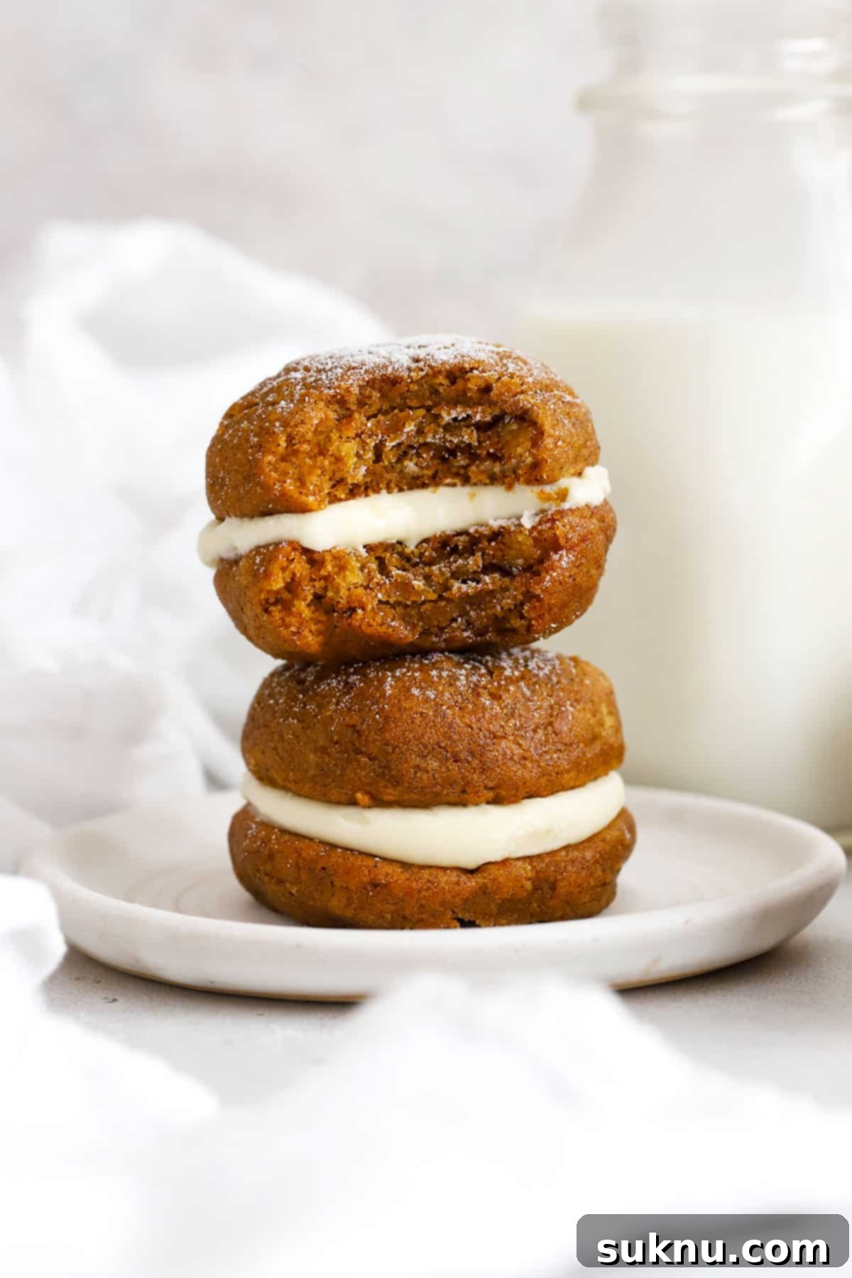 gluten-free pumpkin whoopie pies with cream cheese frosting stacked on a white plate