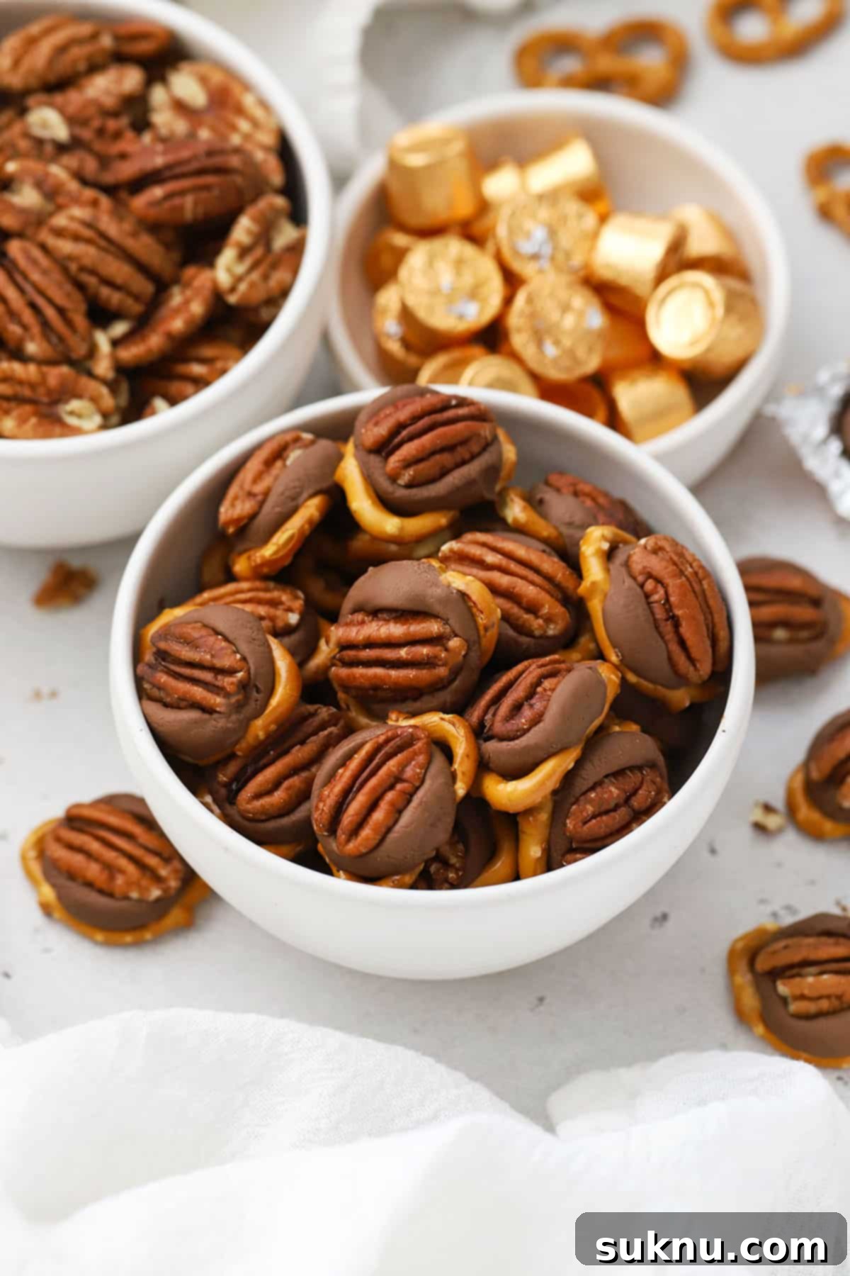 Gluten-Free Rolo Pretzel Turtles 7 An appetizing close-up of Gluten-Free Rolo Turtles, perfectly topped with toasted pecans, on a white surface.