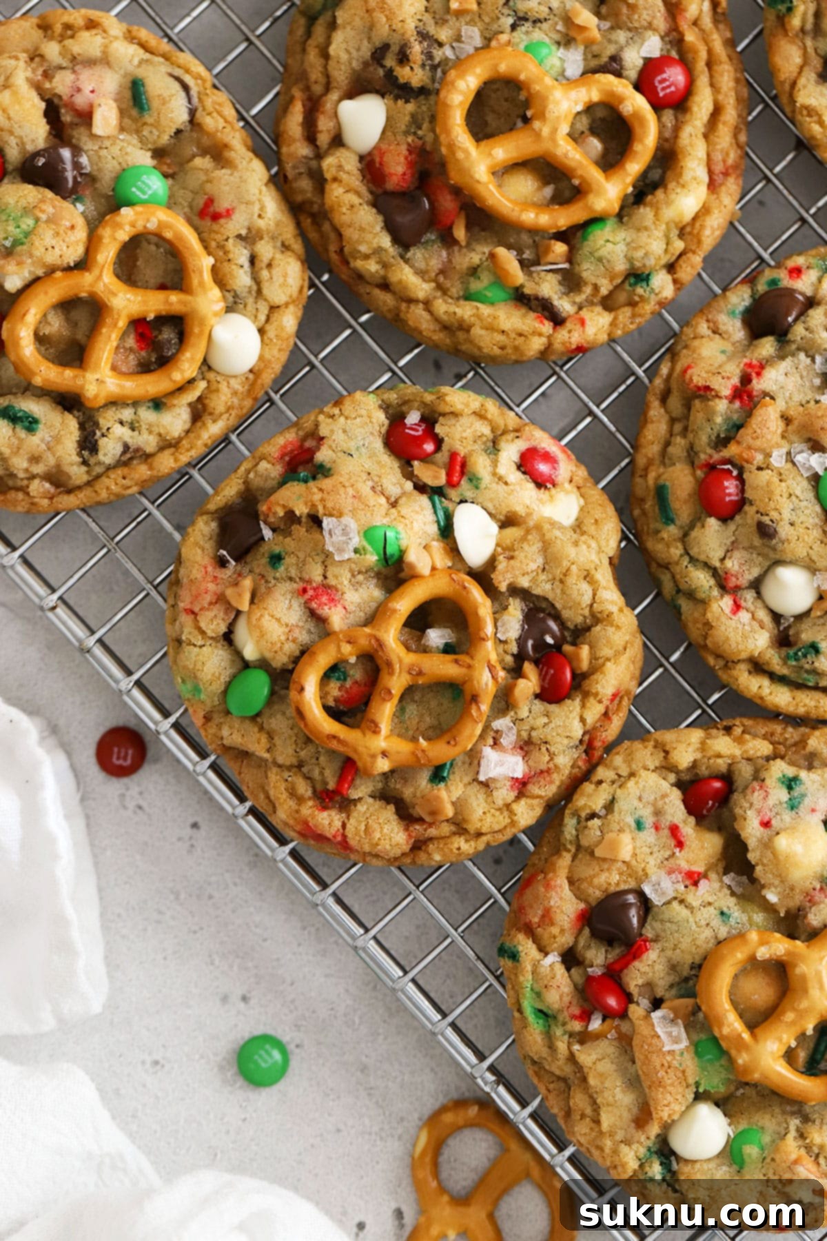 Freshly baked gluten-free Christmas kitchen sink cookies, garnished with extra pretzels and candies, cooling on a wire rack