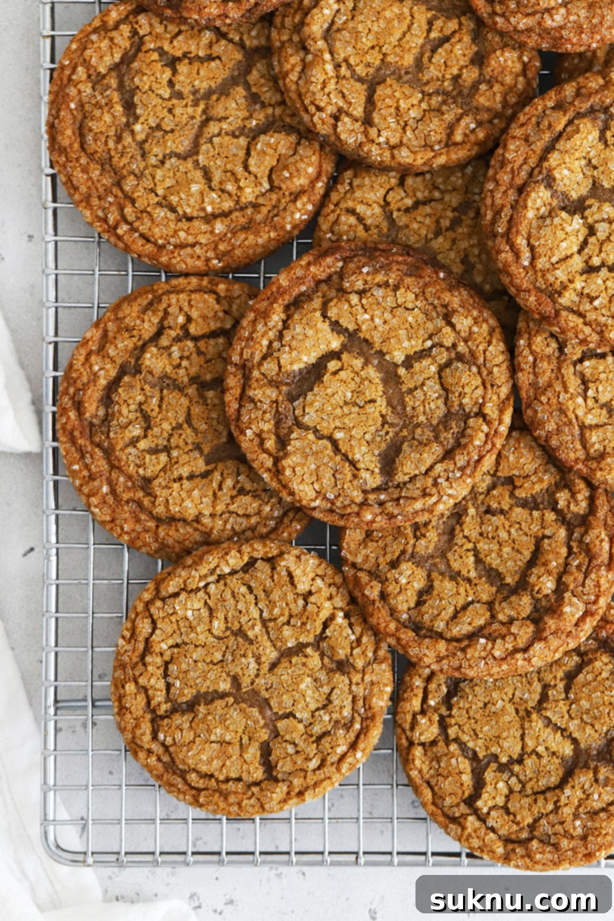 Soft gluten-free molasses cookies cooling on a wire rack, showcasing their crinkled texture.
