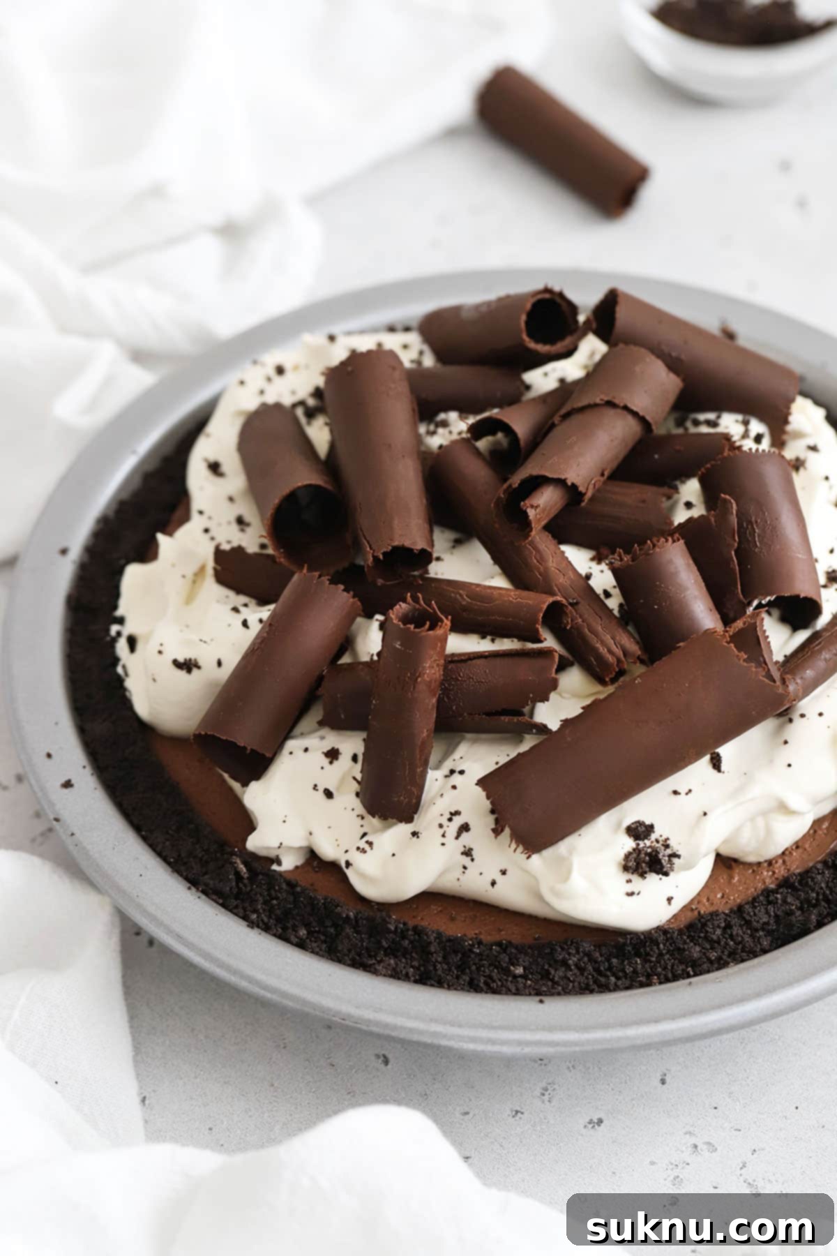 Decadent Gluten-Free Chocolate Pie 6 A stunning three-layered gluten-free chocolate pie, adorned with fluffy whipped cream and an abundance of elegant chocolate curls, ready to be enjoyed.