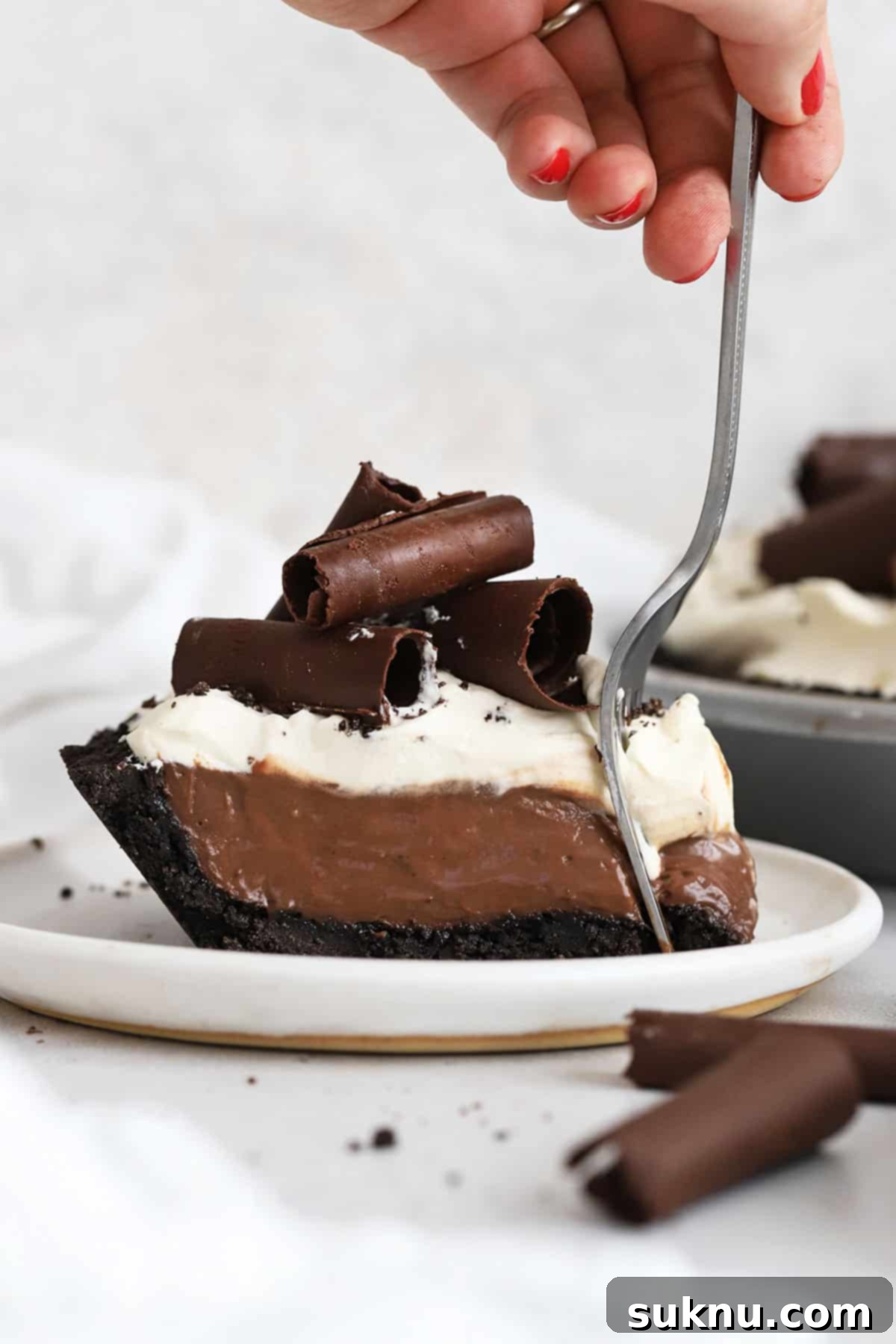Decadent Gluten-Free Chocolate Pie 7 A fork taking a delicious bite of gluten-free chocolate cream pie, showing the creamy filling, crunchy crust, and fluffy whipped cream.