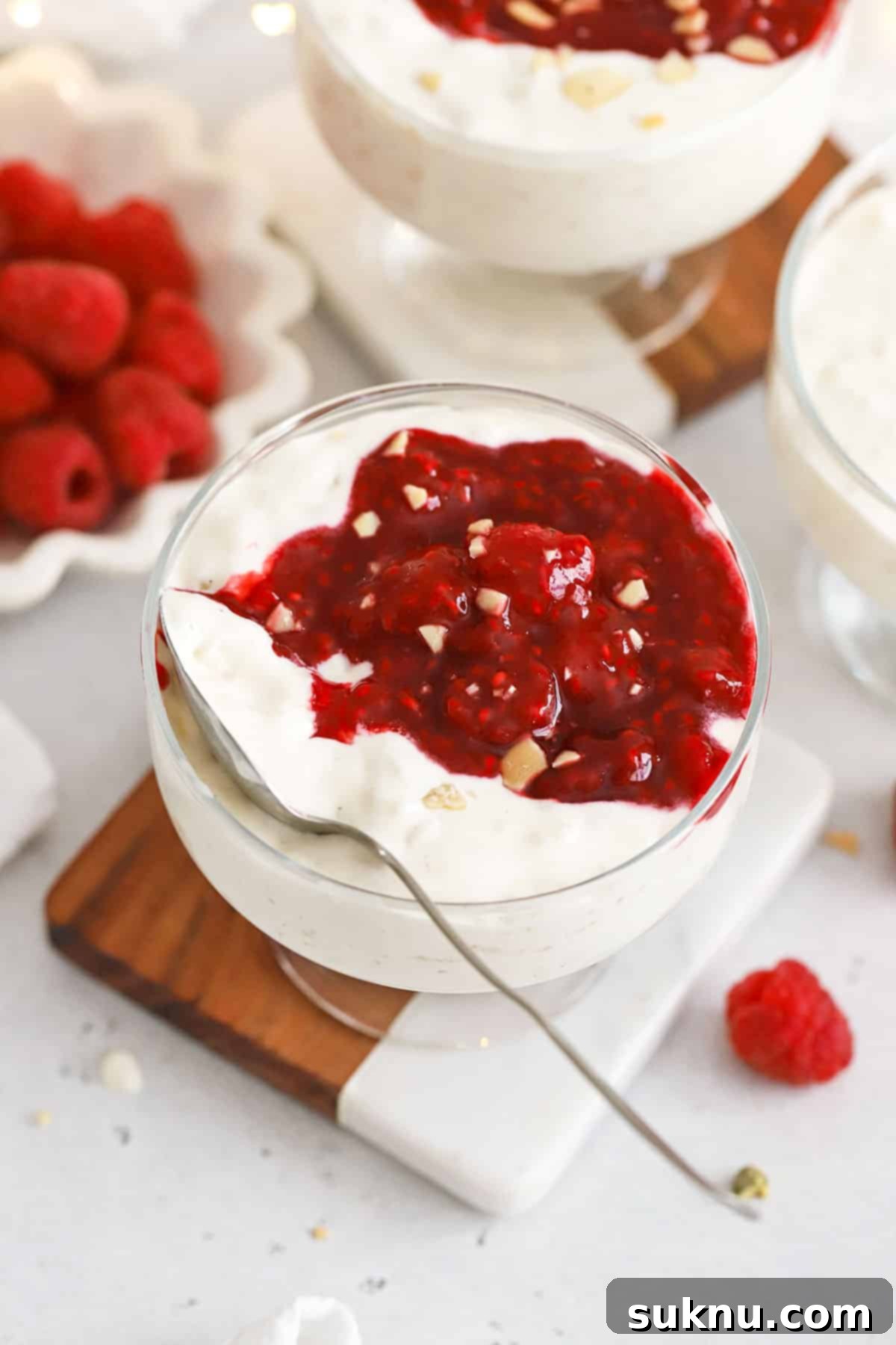 Danish rice pudding in elegant dessert bowls topped with bright raspberry sauce, ready for a festive celebration.
