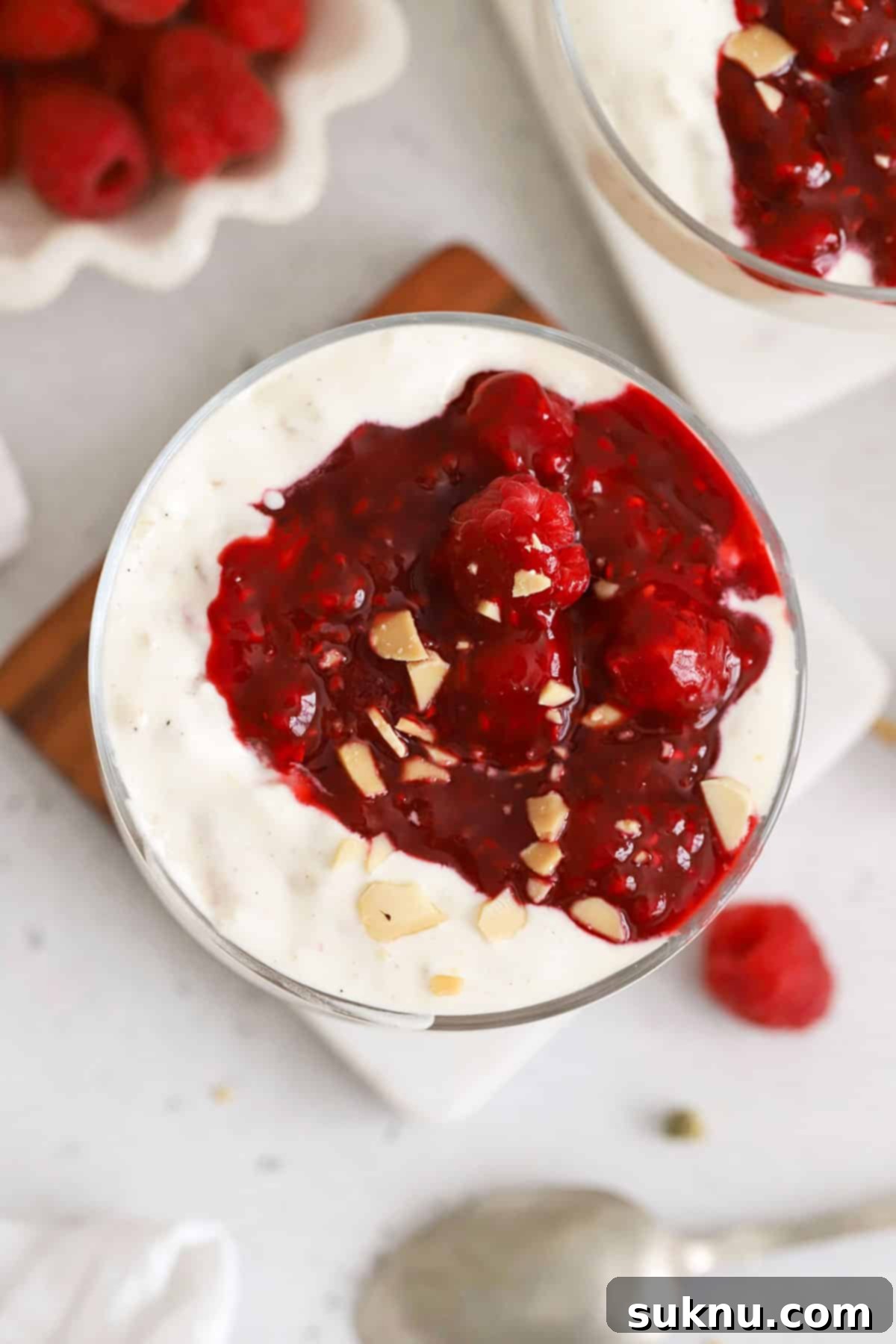 A beautifully presented bowl of Risalamande, Danish rice pudding, generously topped with a rich raspberry sauce.