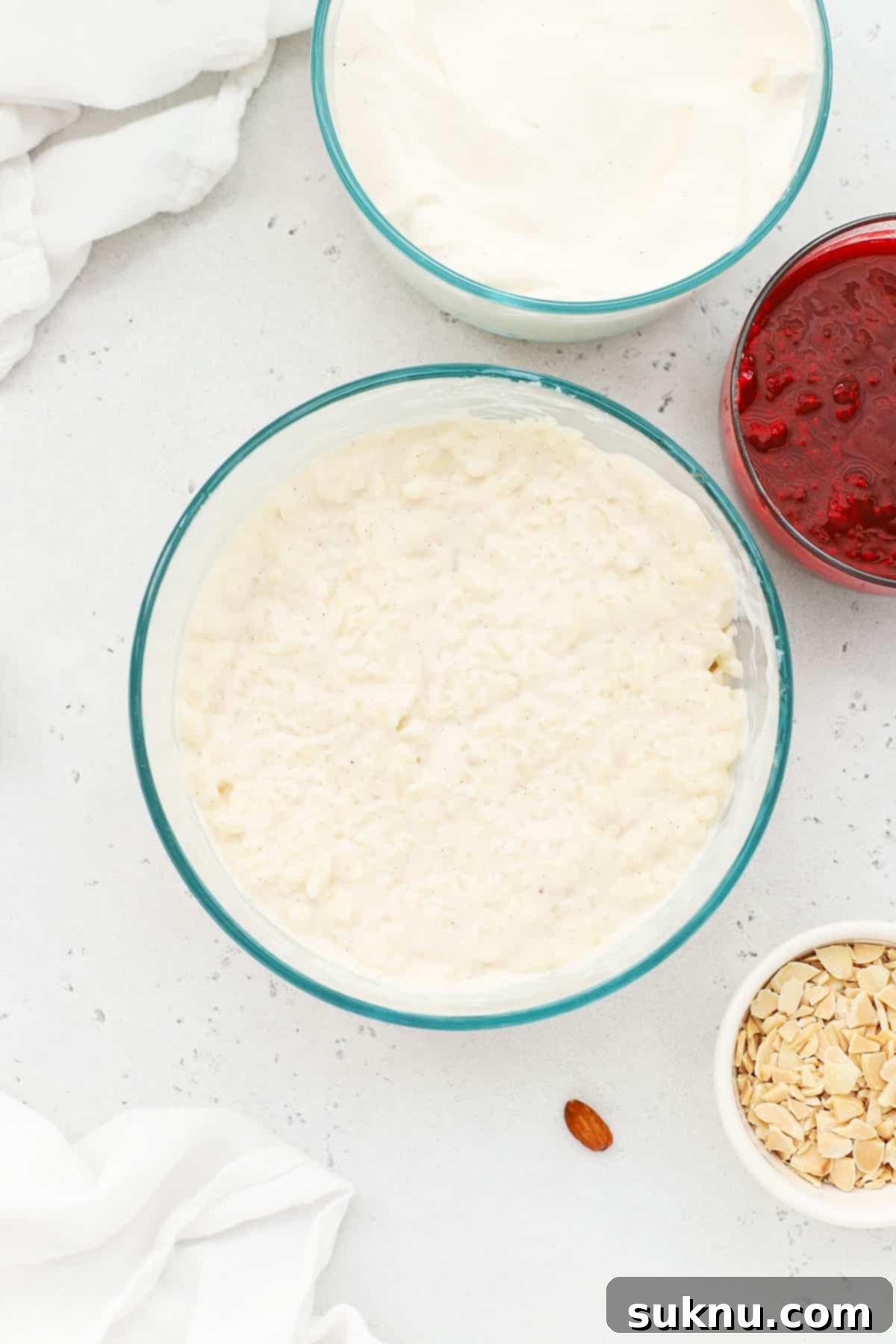 Essential ingredients laid out for making traditional Danish rice pudding, Risalamande, including rice, milk, cream, and almonds.