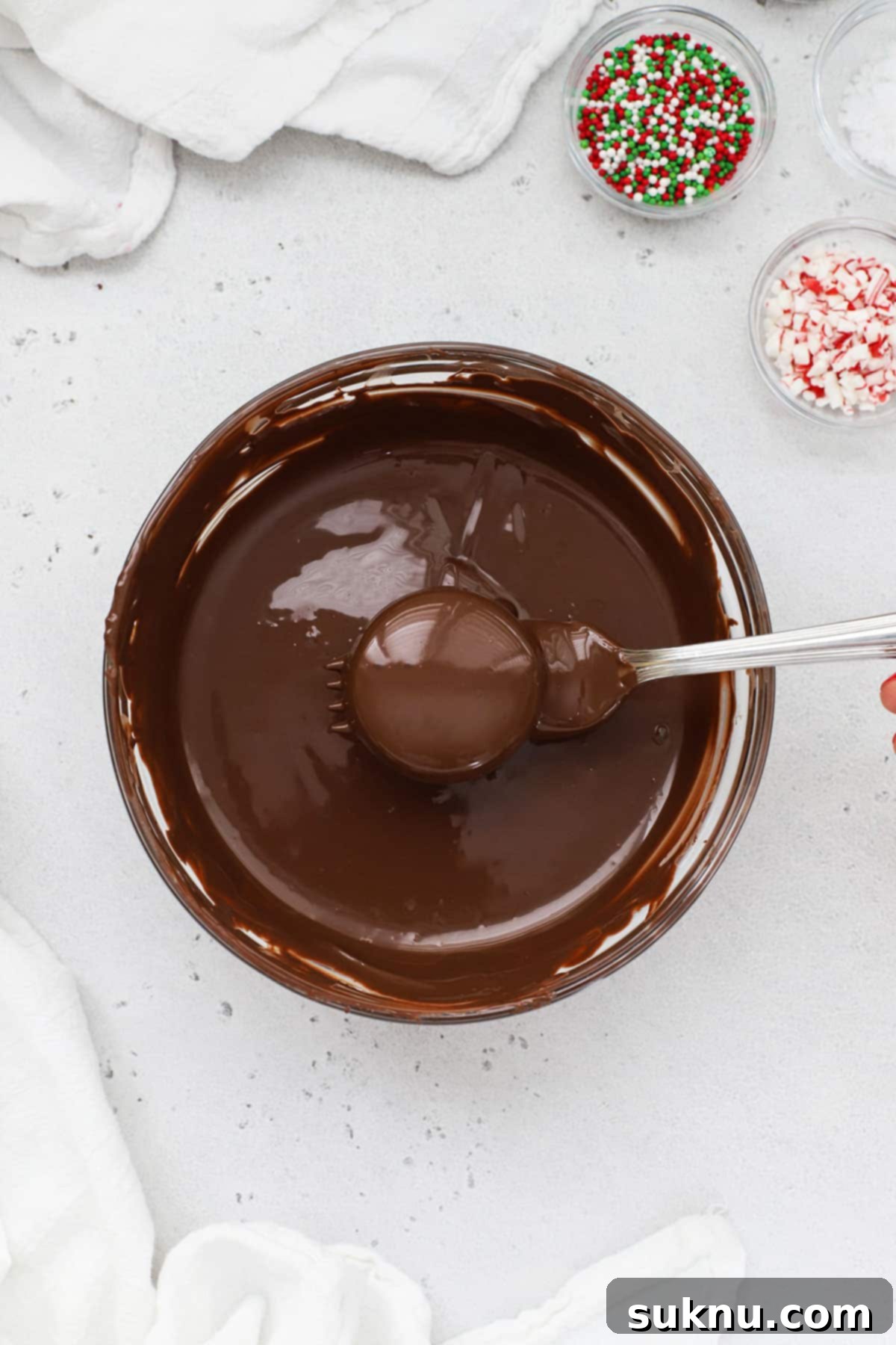 No-Bake Chocolate Dipped Oreos 4 Close-up of a gluten-free Oreo cookie being gently dipped into a bowl of smooth, melted chocolate candy melts.