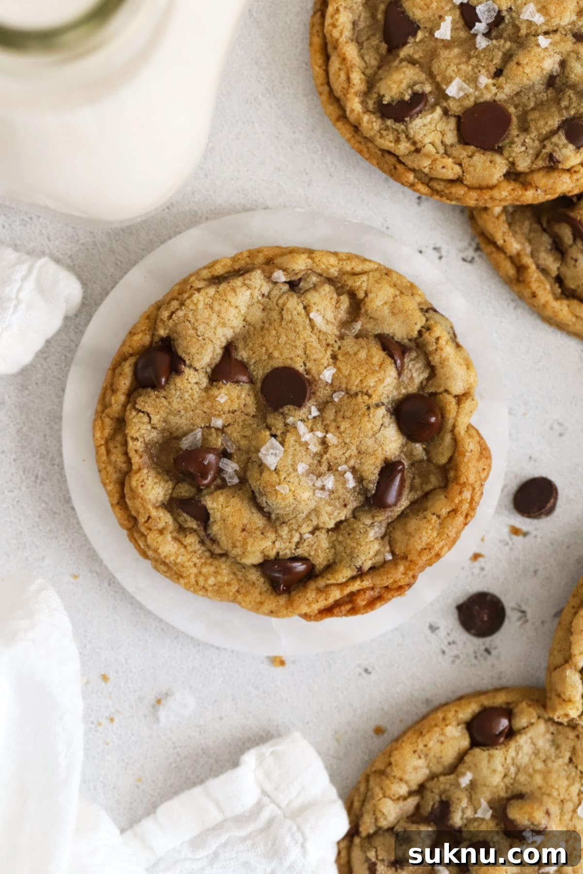 Gluten-free brown butter chocolate chip cookies with a jar of milk, highlighting their perfect texture and golden hue.