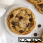 Gluten-free brown butter chocolate chip cookies with a jar of milk, highlighting their perfect texture and golden hue.