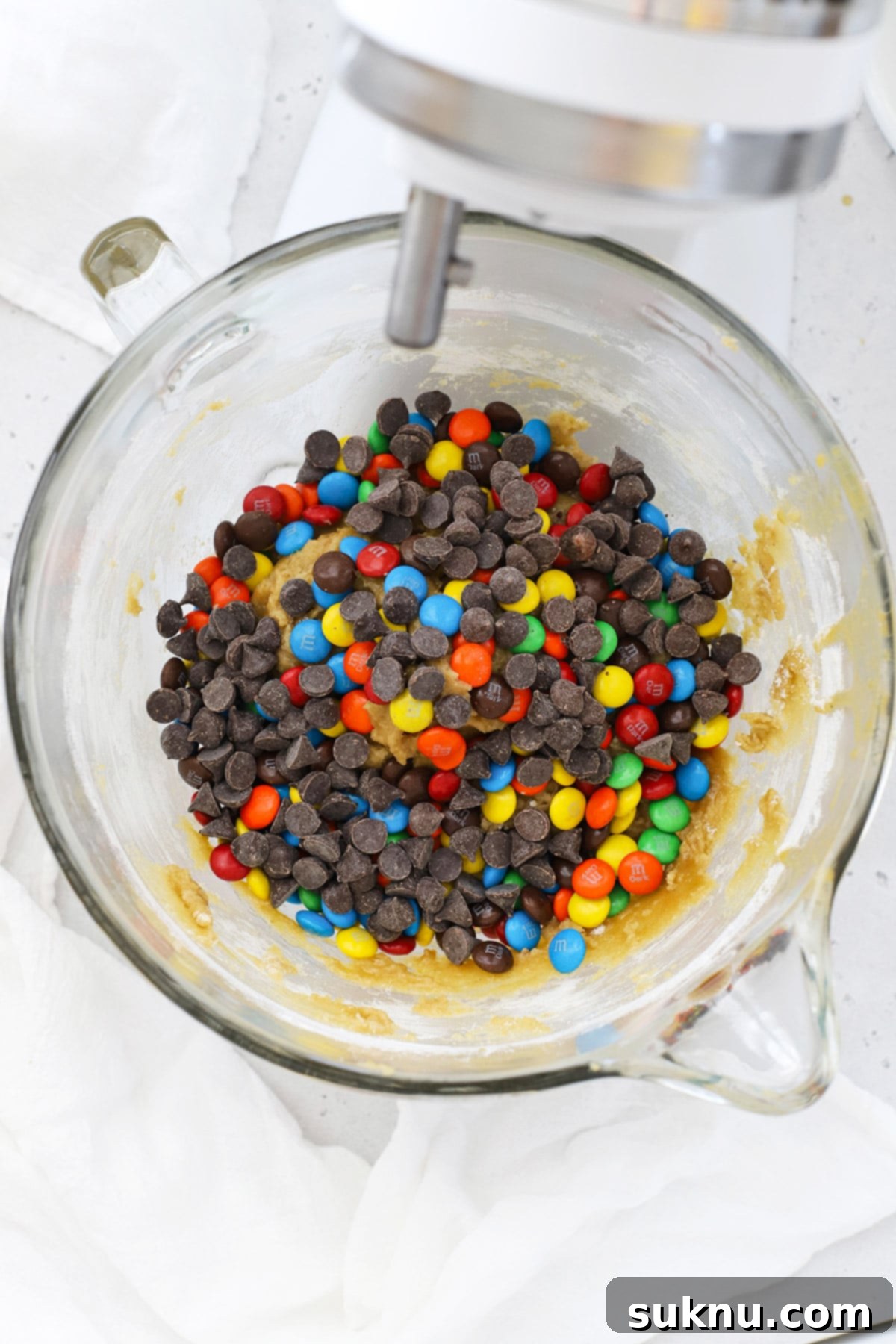 Adding colorful M&Ms and classic chocolate chips to gluten-free M&M cookie dough.