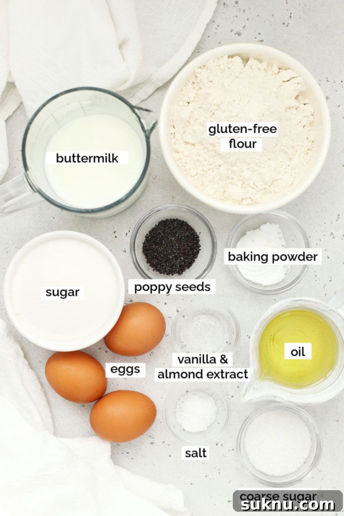 Assortment of gluten-free almond poppy seed muffin ingredients laid out in small bowls, including flour, sugar, poppy seeds, and extracts, ready for baking.