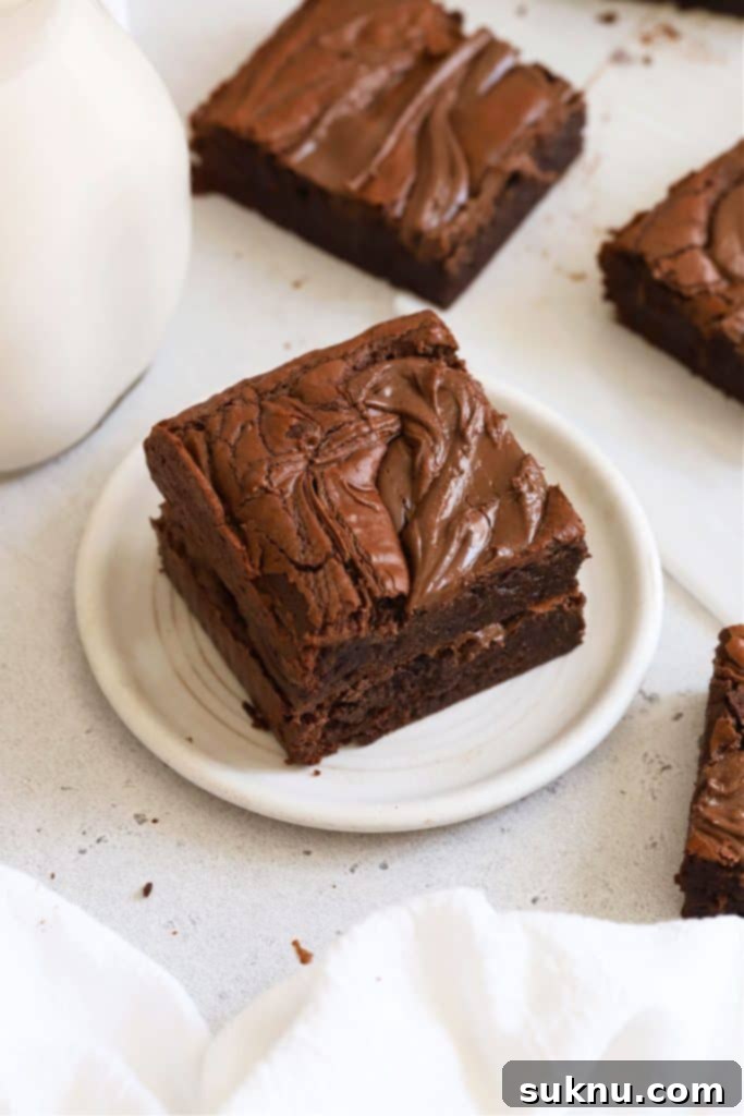 Gluten-free Nutella brownies stacked on a white plate, showing the rich swirl.
