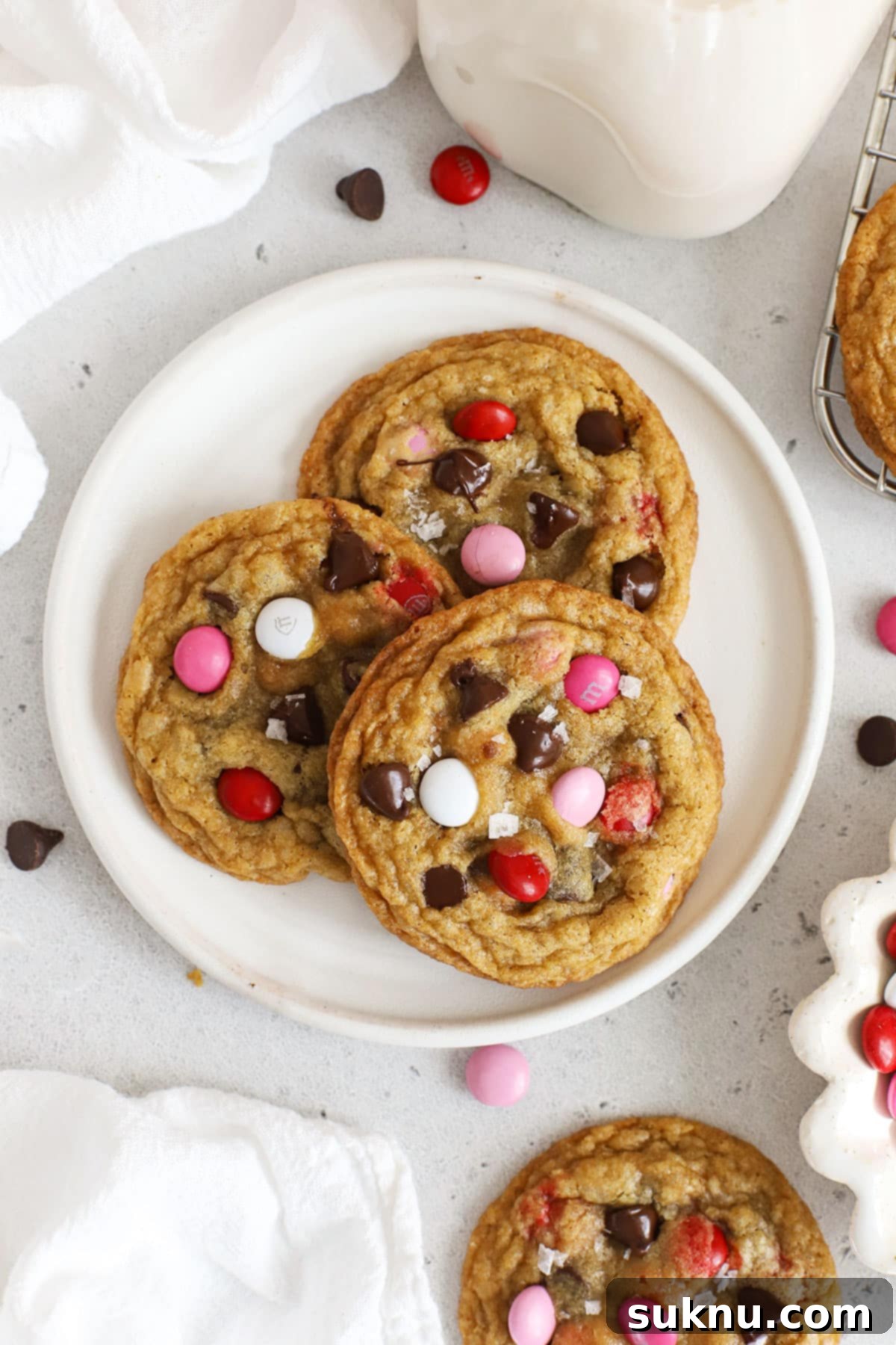 Three gluten-free Valentine's cookies with m&ms on a white plate