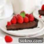 A slice of gluten-free chocolate ganache tart on a white plan