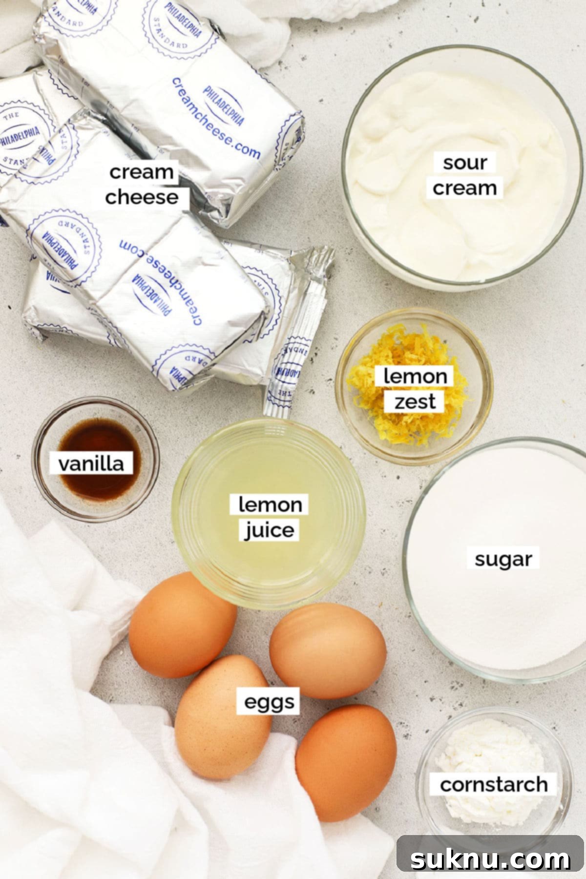 A vibrant selection of ingredients for making gluten-free lemon cheesecake, including lemons, graham crackers, and cream cheese.