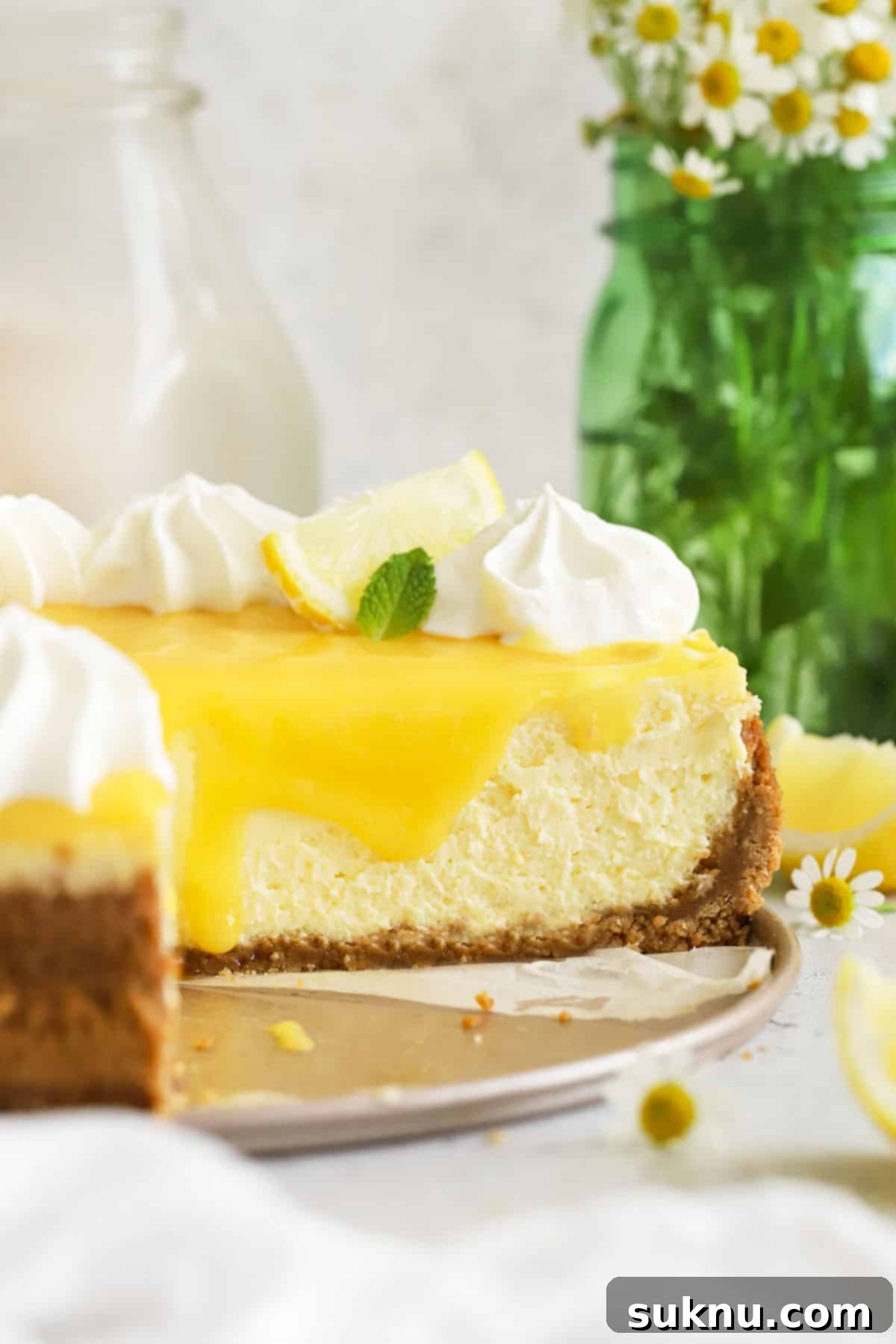 A beautifully decorated gluten-free lemon cheesecake on a elegant dessert platter, ready for serving.