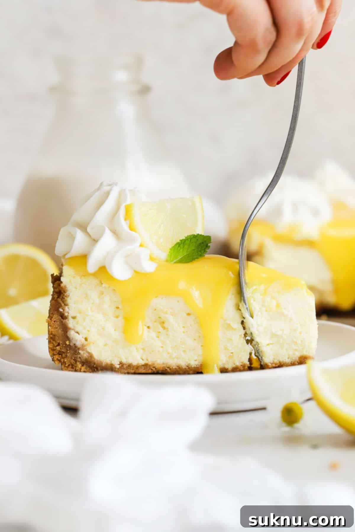 A fork taking a bite from a luscious slice of gluten-free lemon cheesecake, highlighting its creamy texture and rich toppings.
