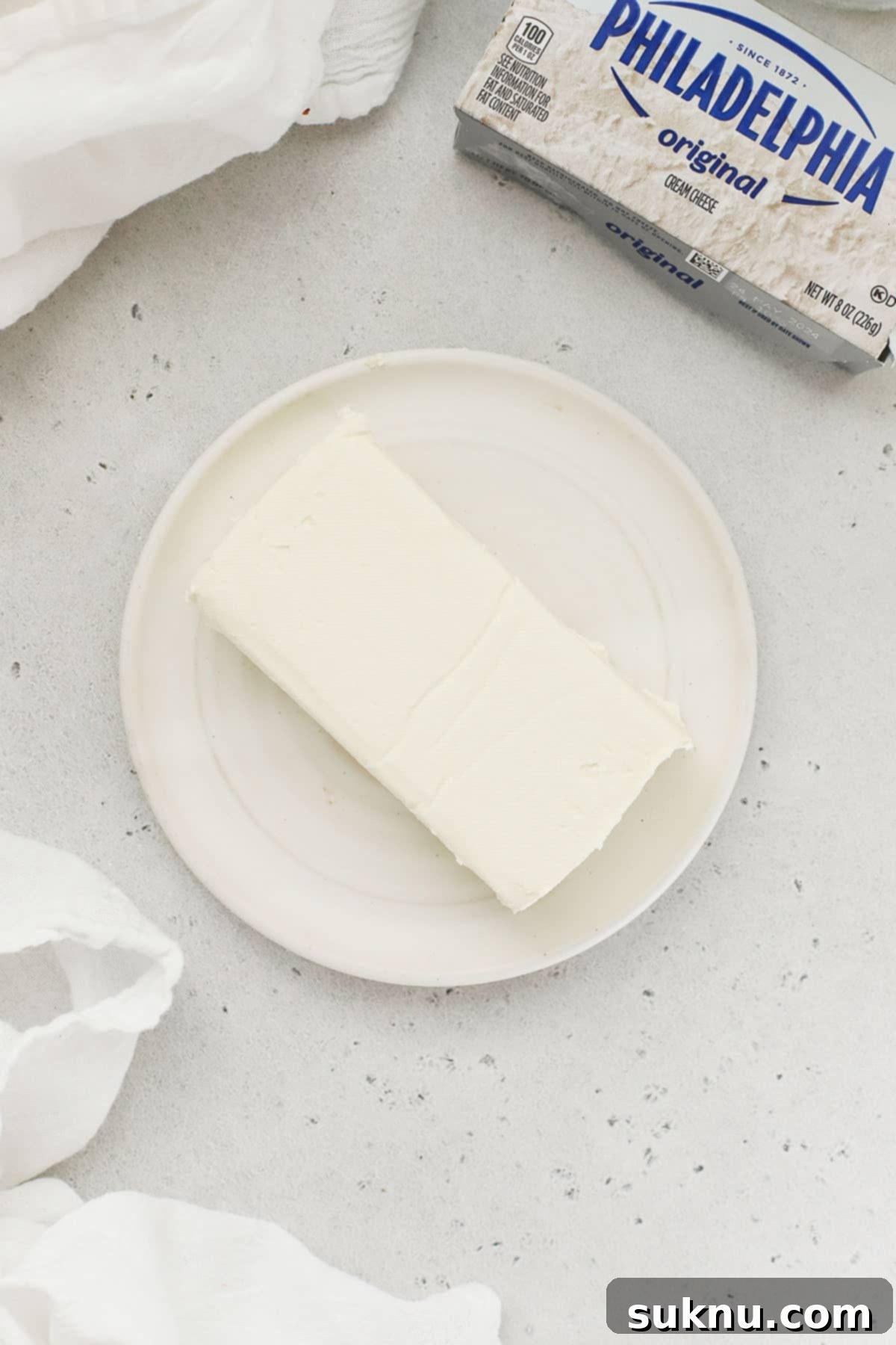 Soft Cream Cheese in Minutes 4 A block of cream cheese gently softening on a white plate at room temperature