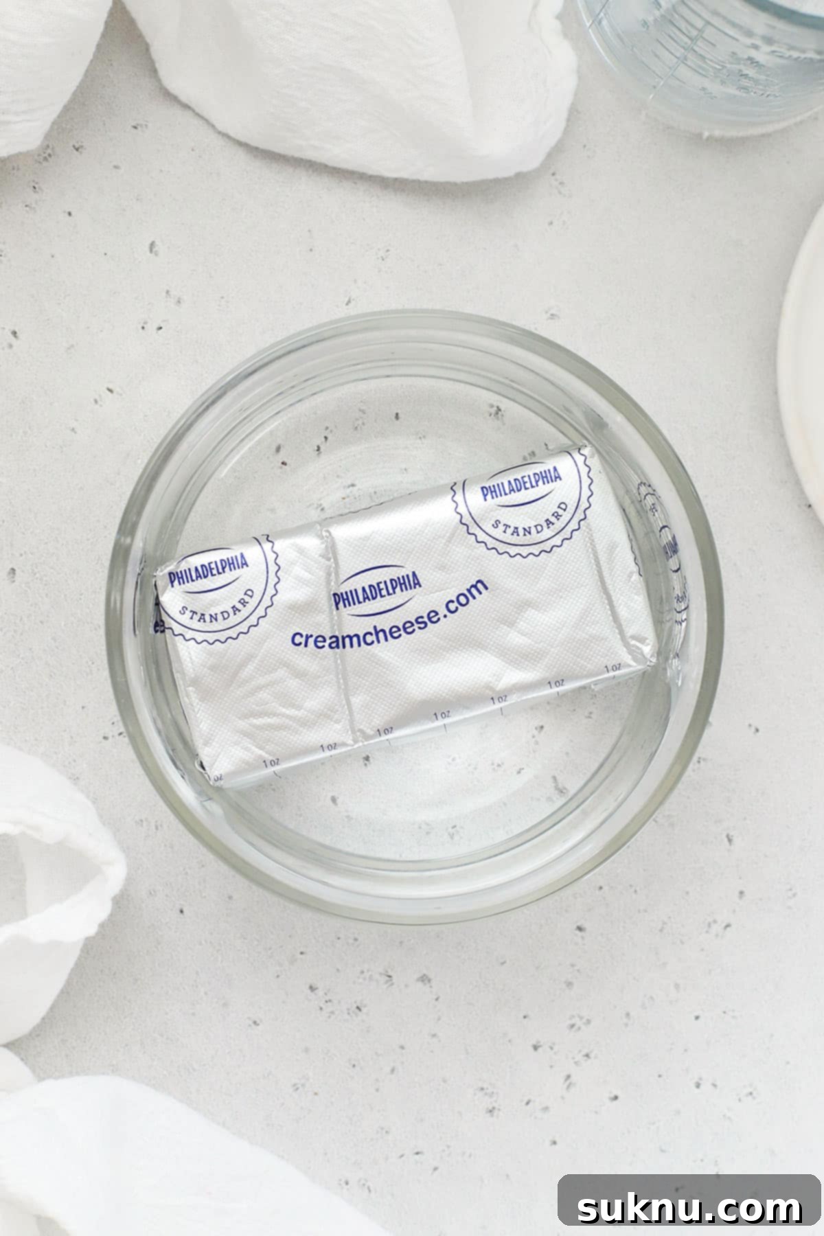 Soft Cream Cheese in Minutes 6 A foil-wrapped block of cream cheese submerged in a container of warm water for rapid softening